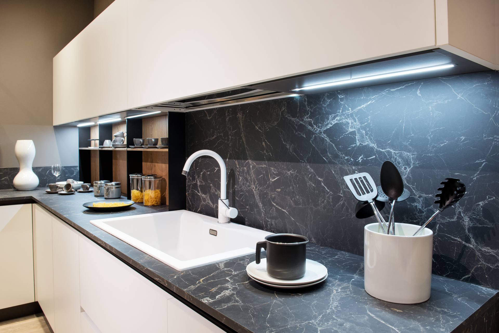 A kitchen with a sink and utensils on the counter.