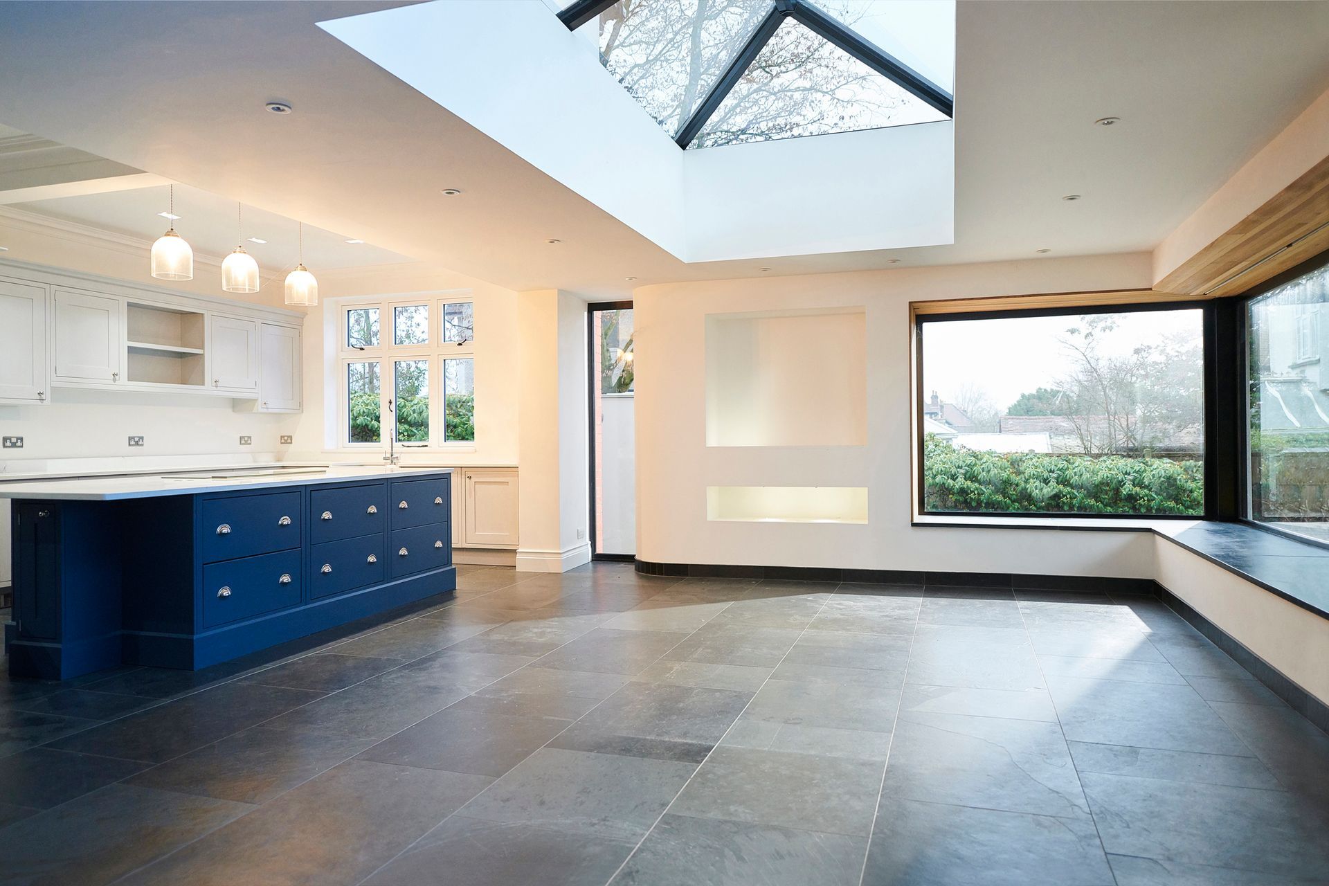 An empty kitchen with blue cabinets and a large window.
