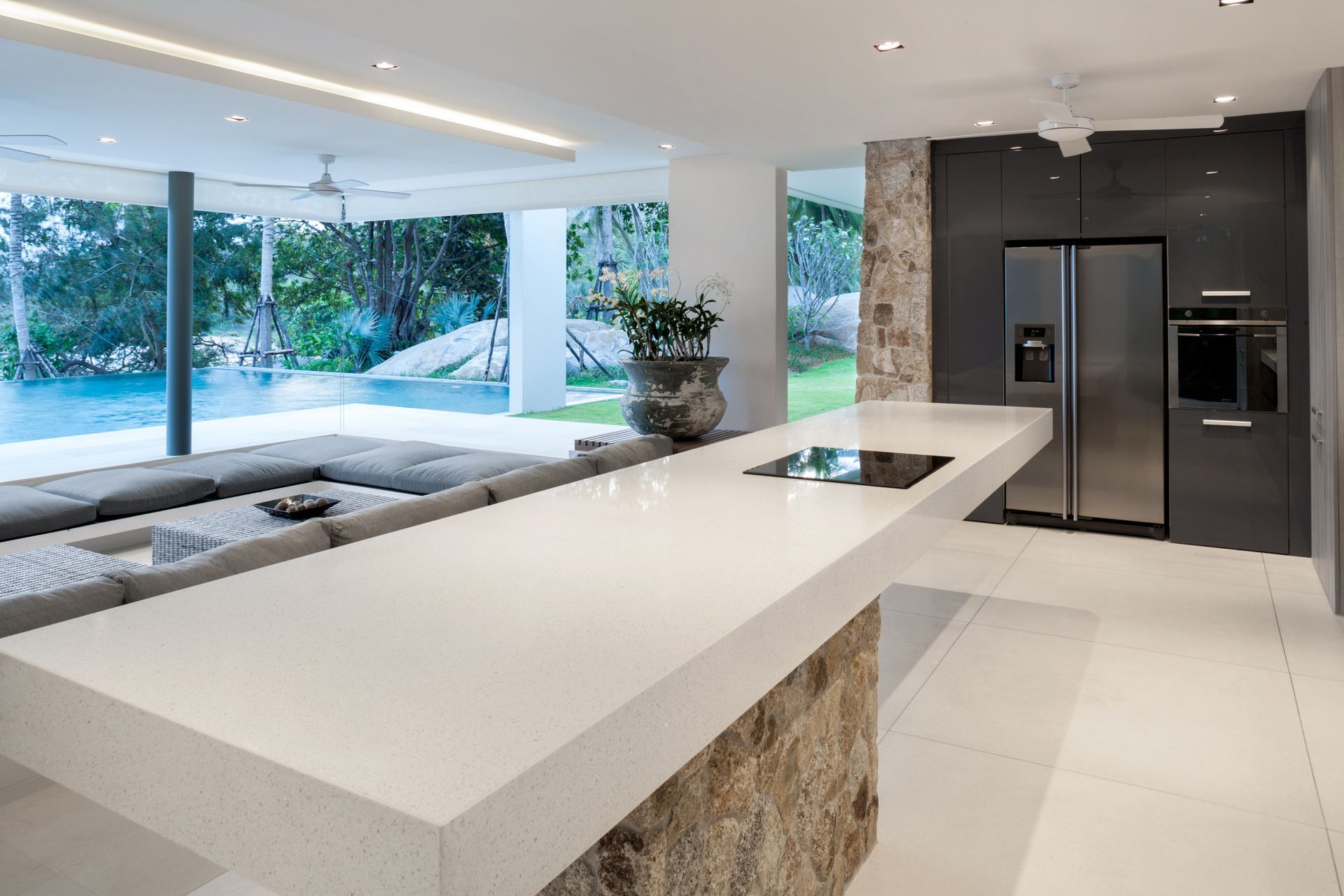 A kitchen with a large island and a stainless steel refrigerator