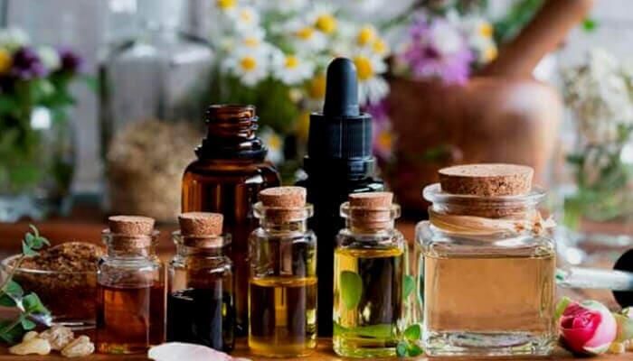 Una mesa cubierta con botellas de aceites esenciales y flores.