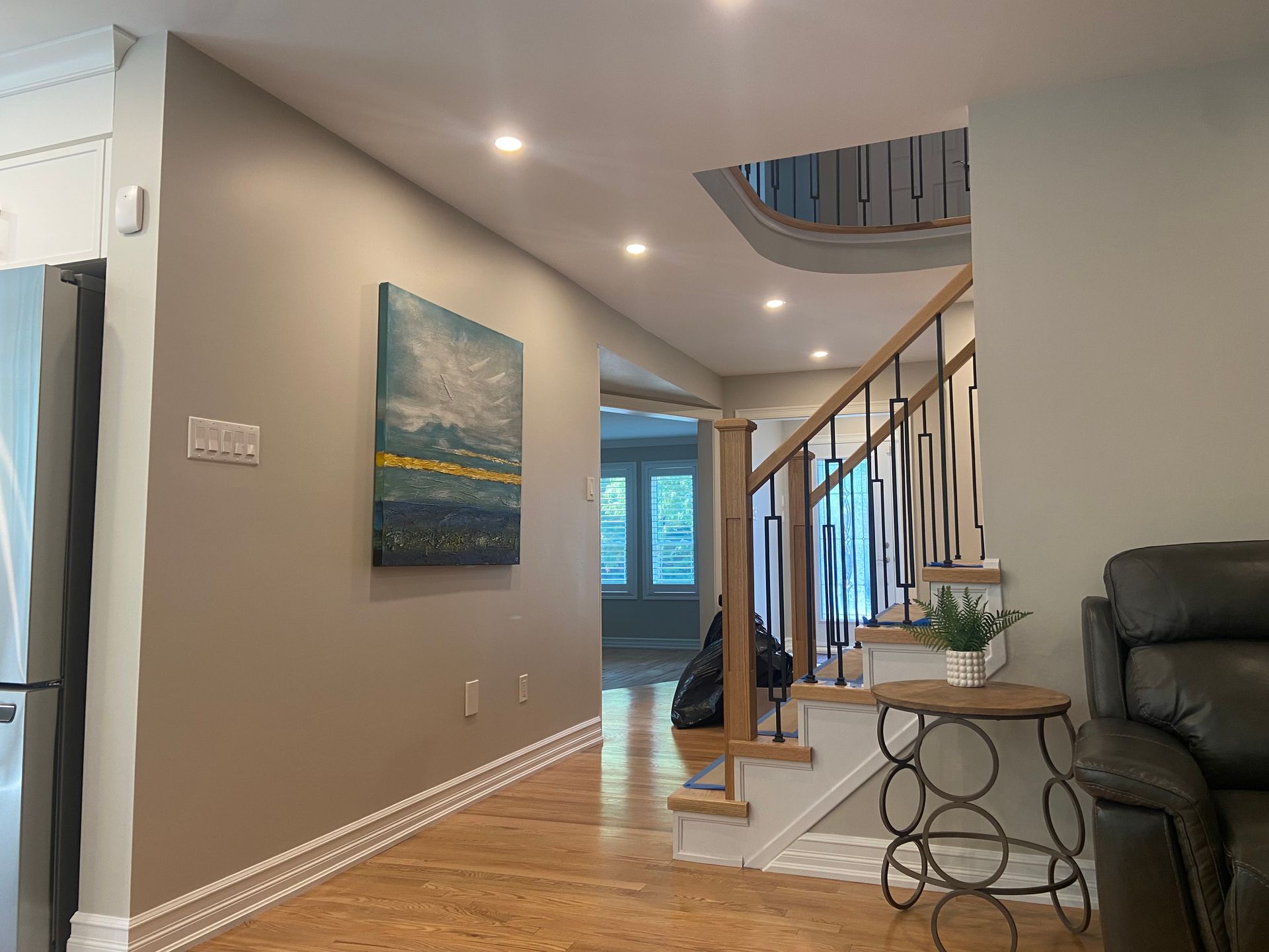 Modern living room hallway with staircase, gray walls, wood floors, and skylight.
