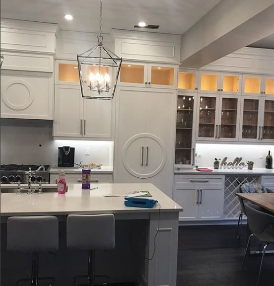 Modern white kitchen with large island, pendant light, and built-in refrigerator under cabinet lighting