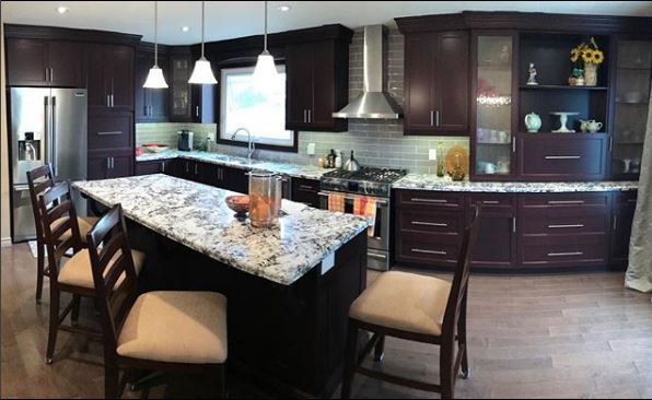Modern kitchen with dark cabinets, granite island, pendant lights, and stainless steel appliances
