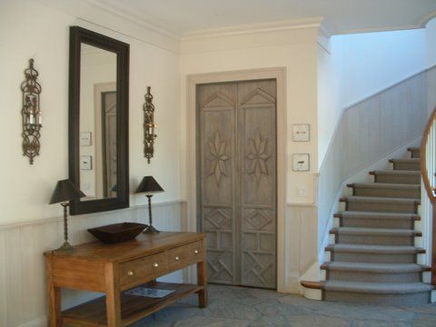 Entryway with staircase, wooden console table, ornate double doors, and mirrored wall decor
