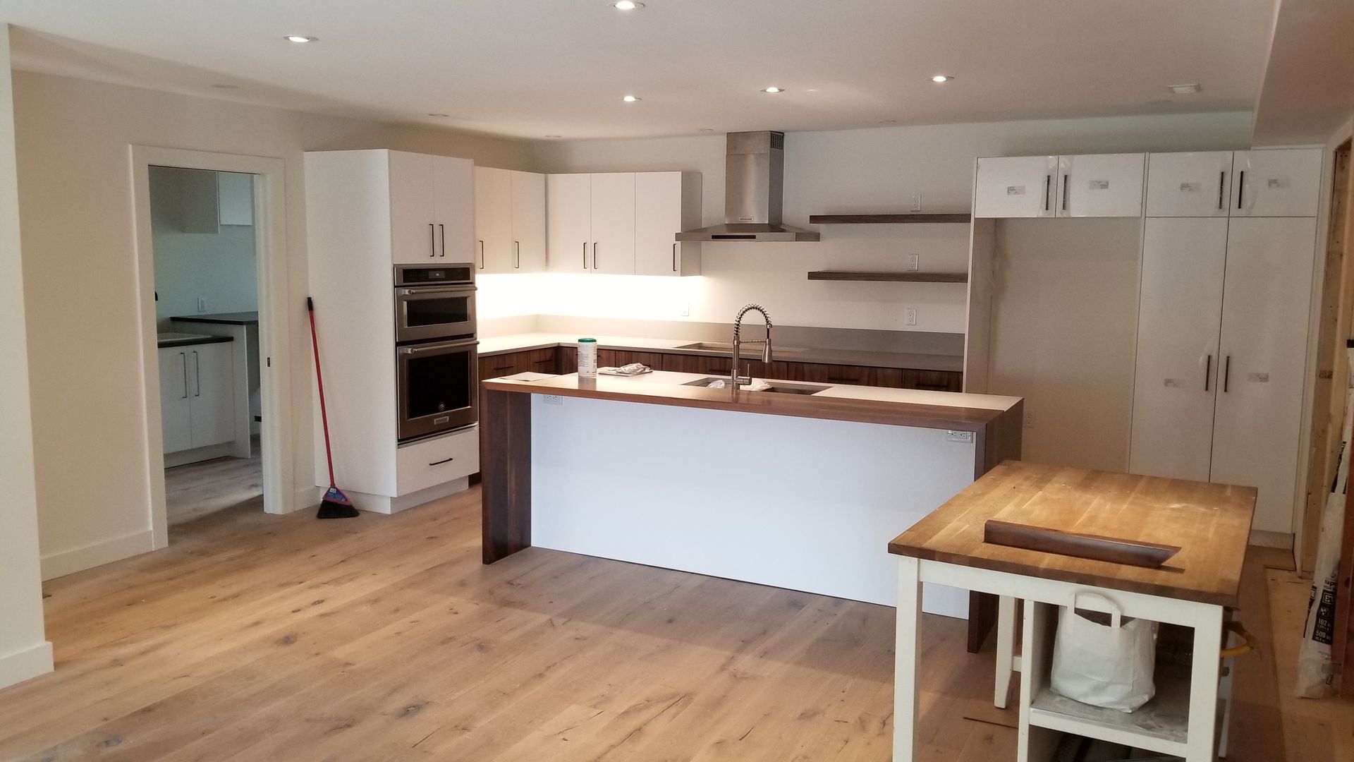 Bright modern kitchen with white cabinets, wood floors, and a central island with sink and stools