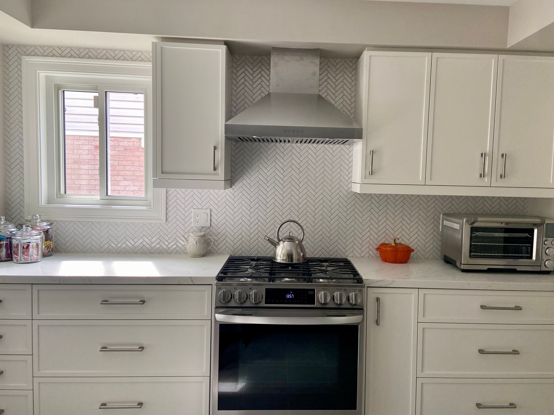 White kitchen with stove, cabinets, counter, microwave, and window over sink