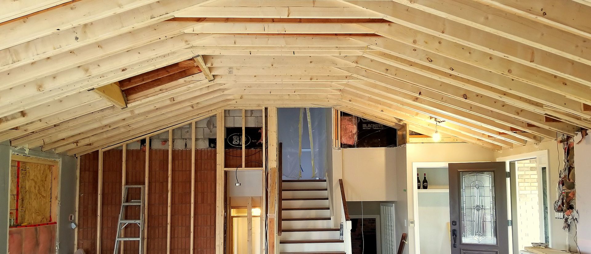 Unfinished interior with exposed wood framing, stairs, and a vaulted ceiling under construction