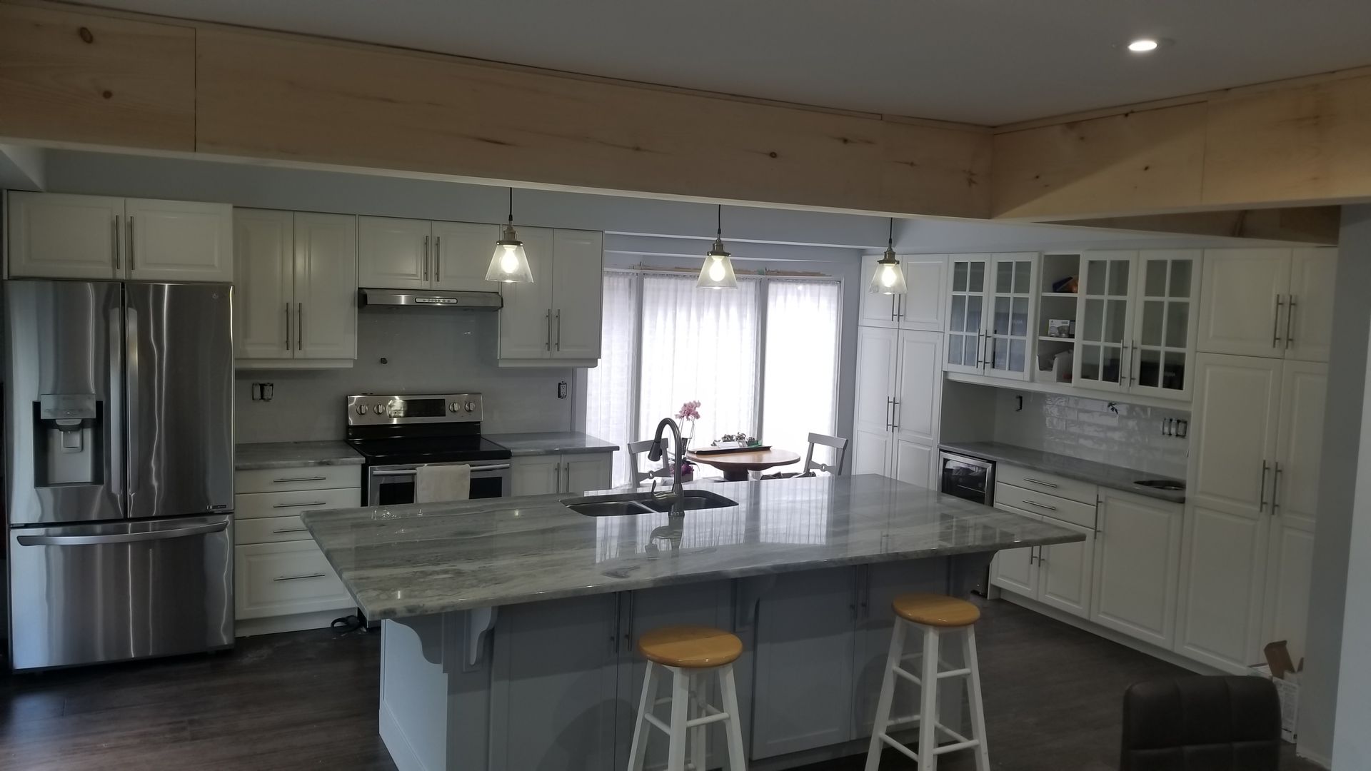 Modern kitchen with stainless steel appliances, white cabinets, and a large island with stools