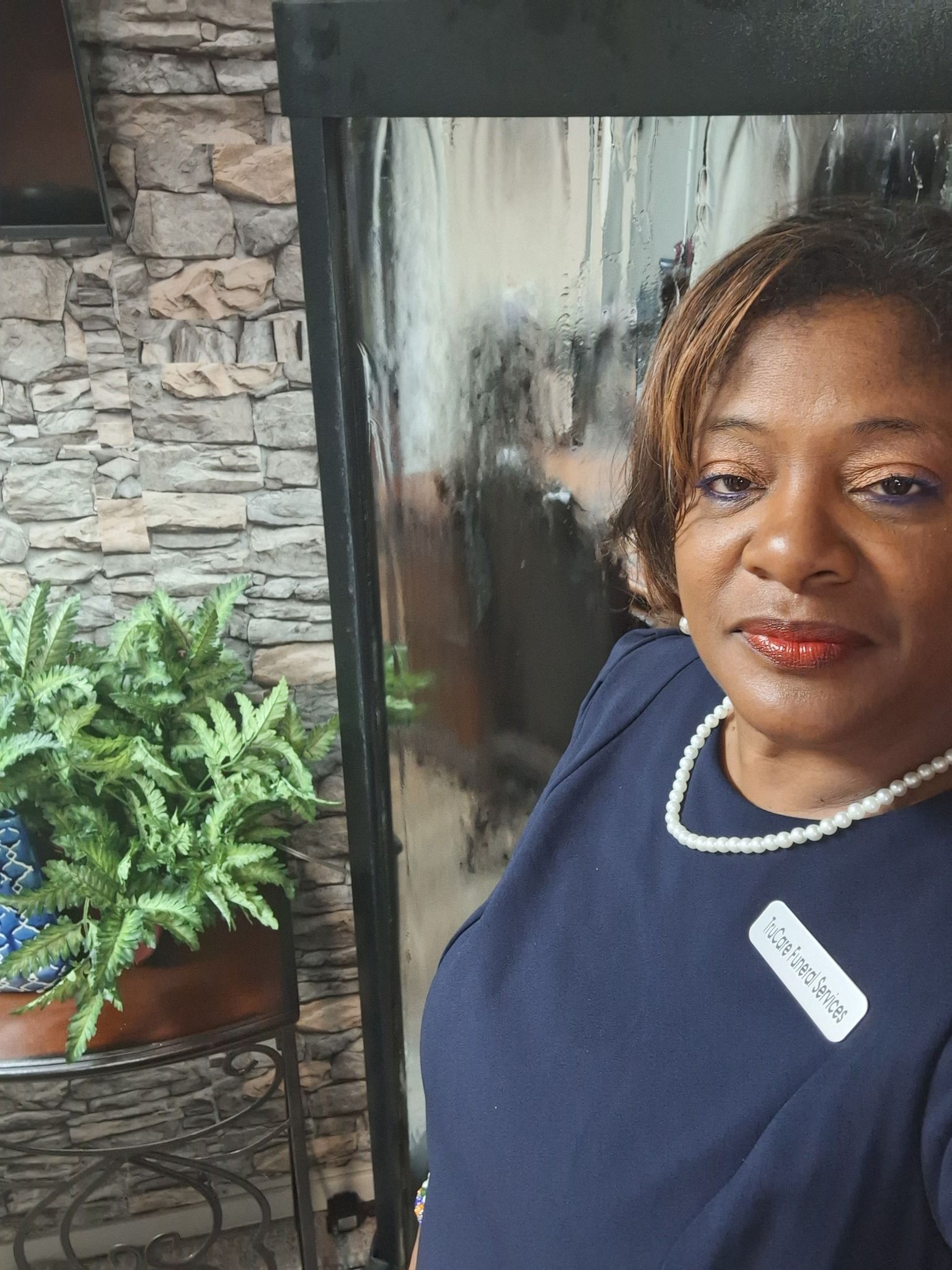 Woman smiling beside indoor plants and stone wall