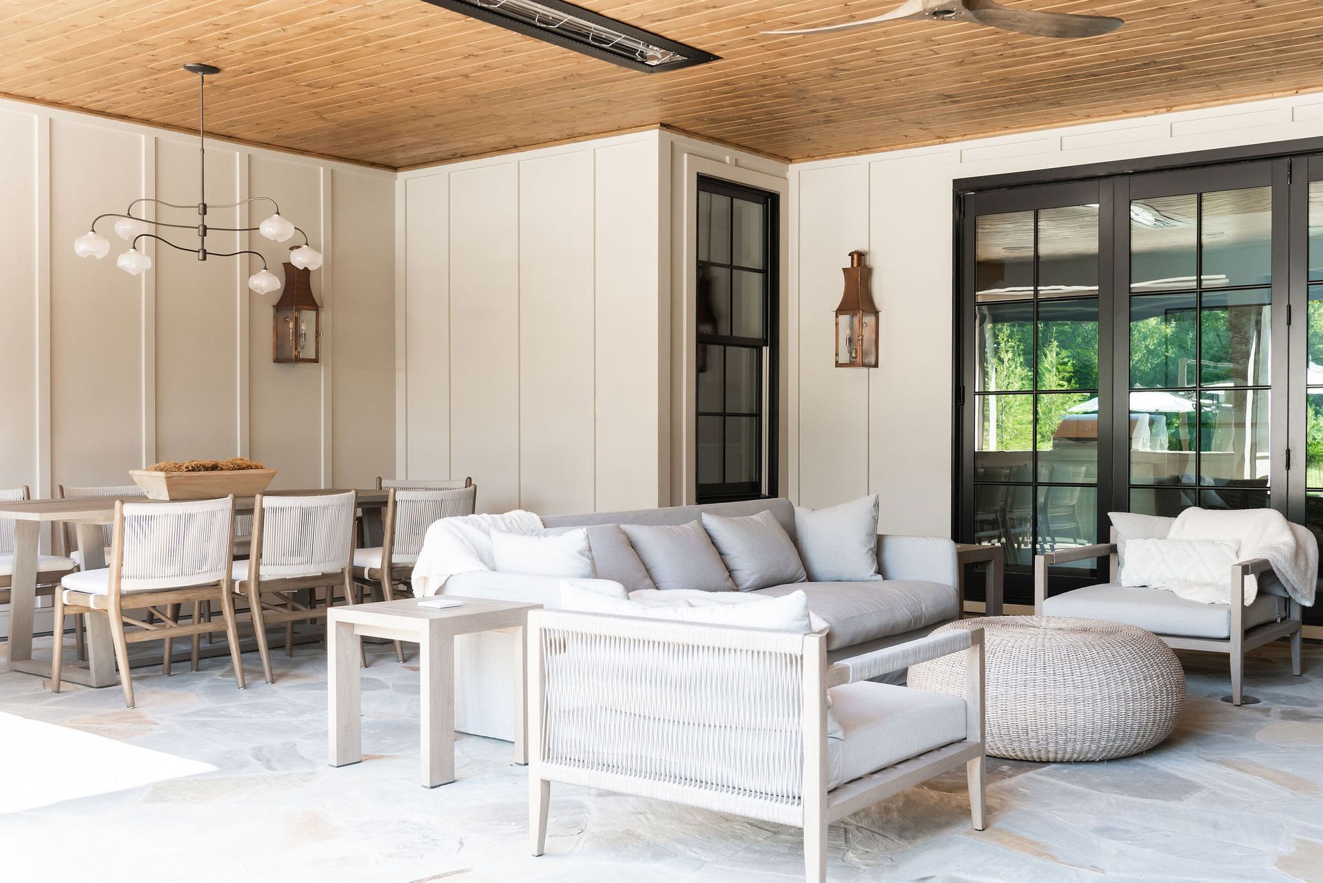 Modern covered patio with white seating, dining table, woven ottoman, and sliding glass doors