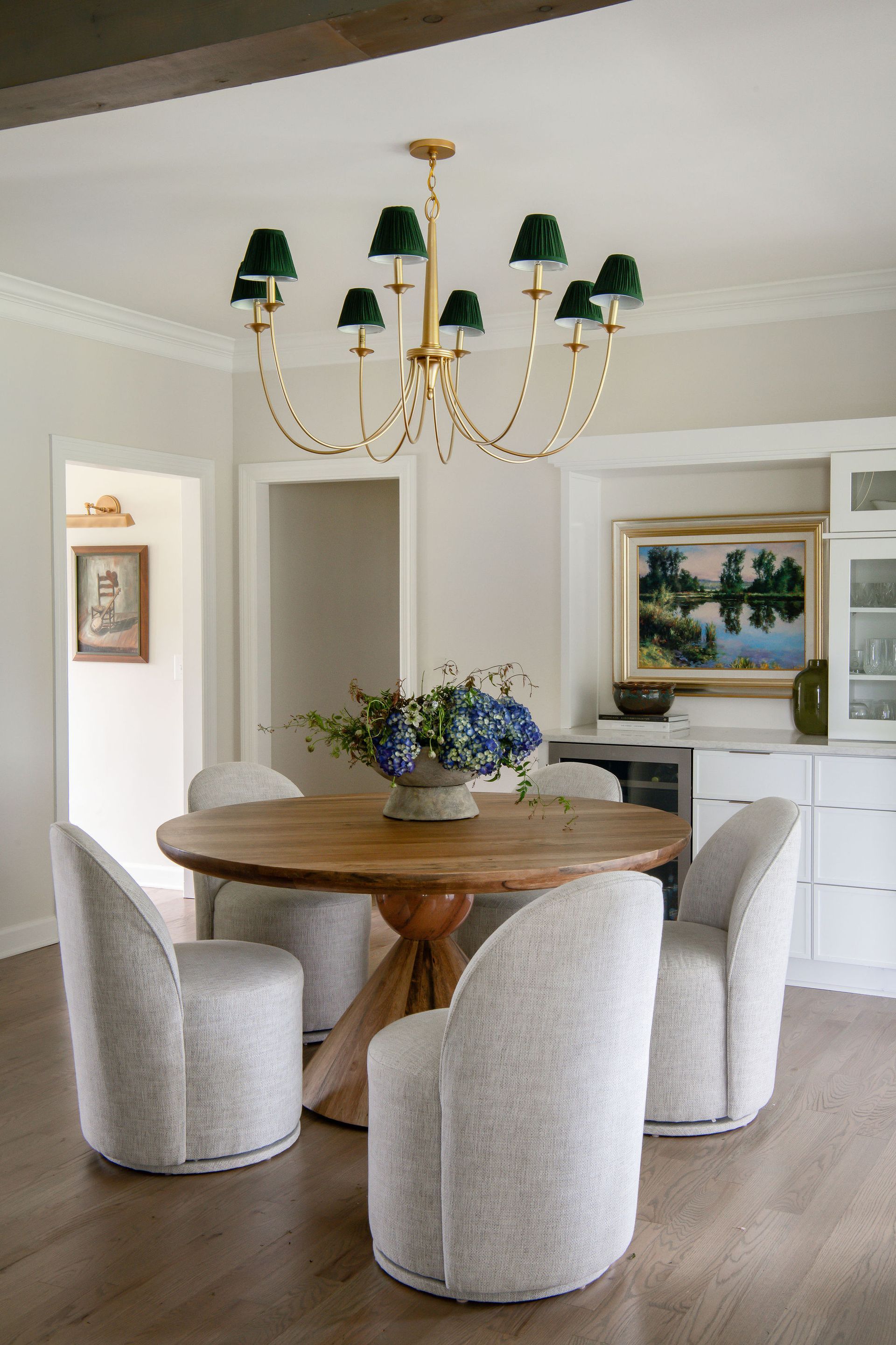 A dining room with a wooden table, curved chairs, and a chandelier with green shades.