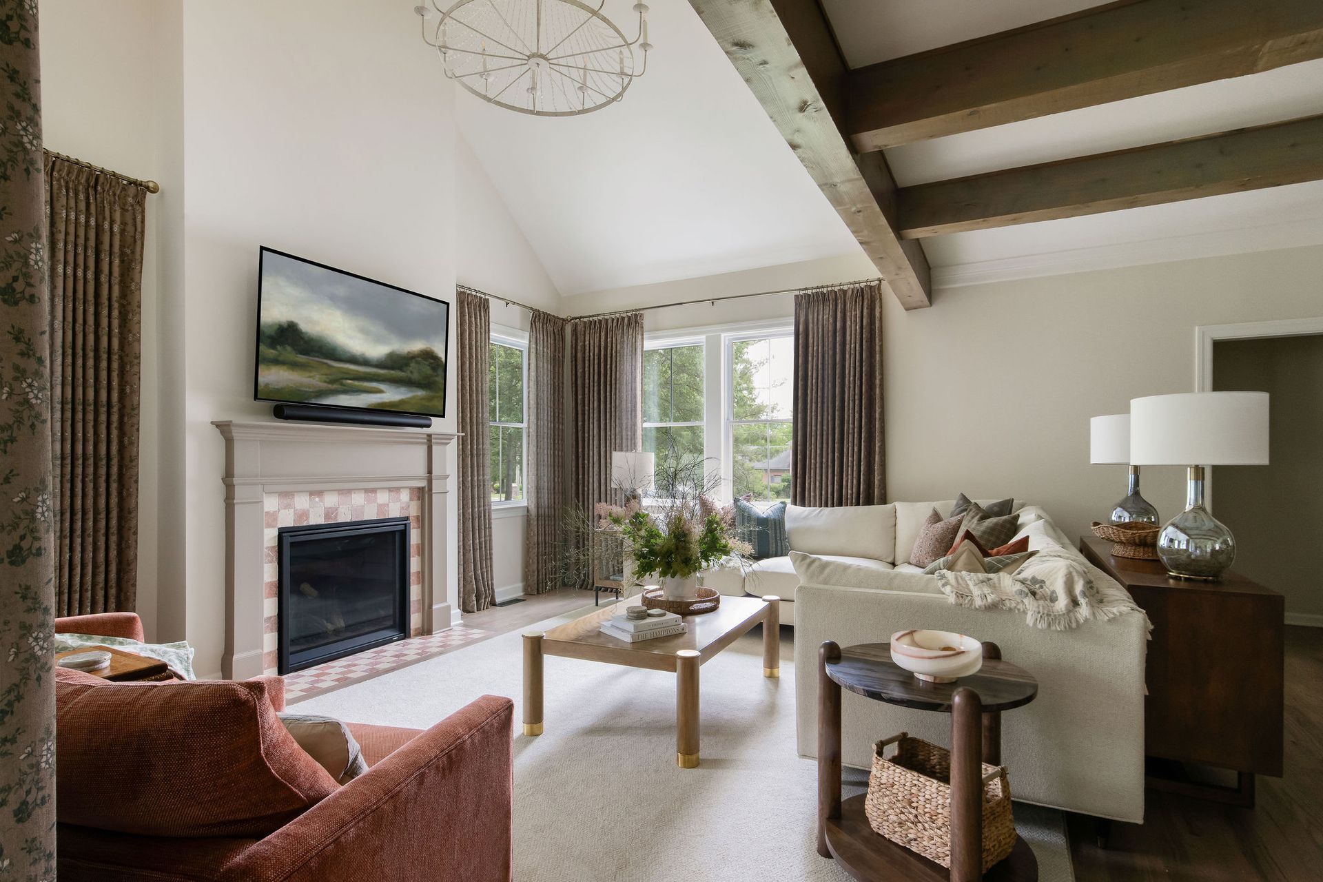 Living room with fireplace, white sofa, and wooden beams. Neutral colors, natural light, and modern decor.