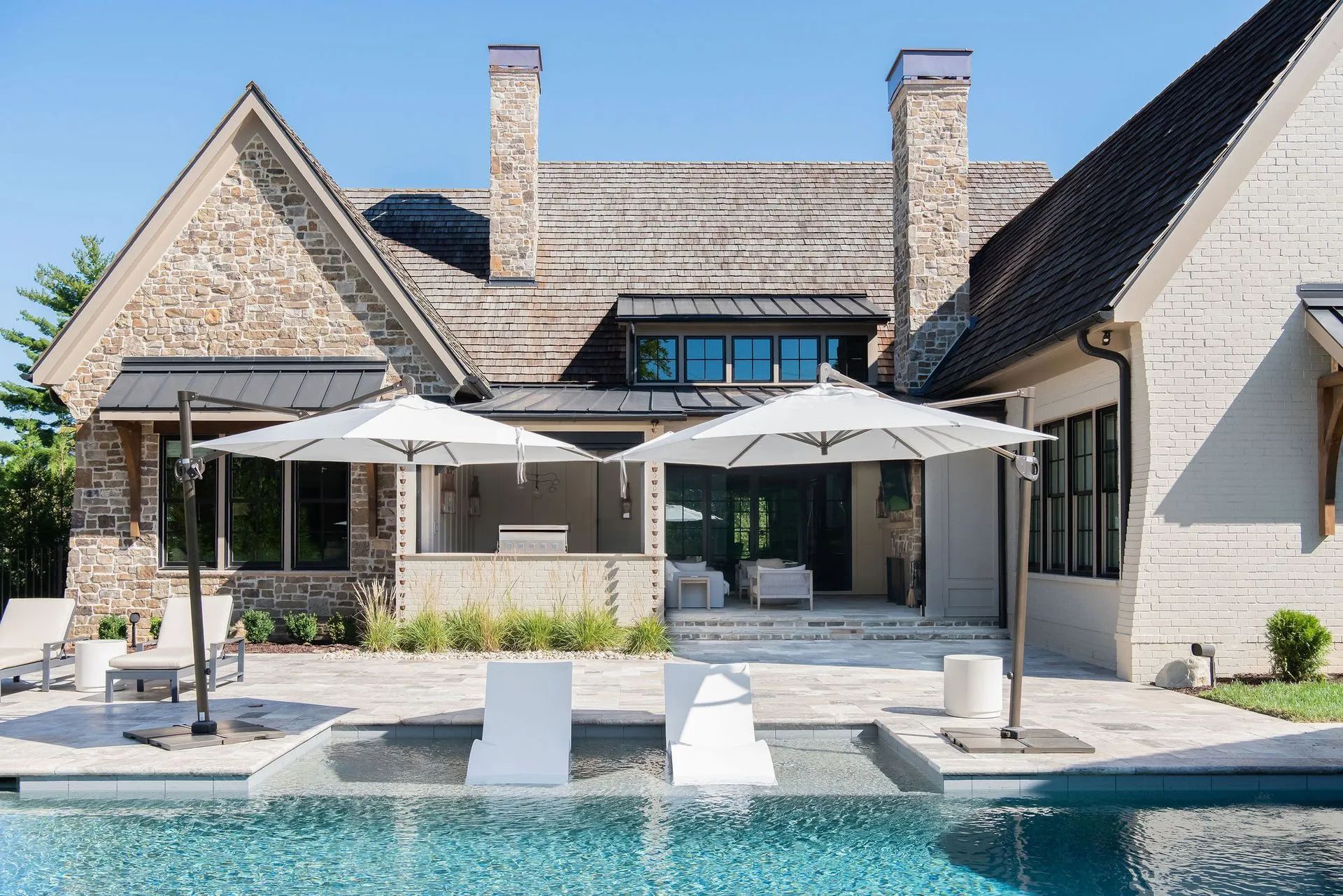 A large house with a pool and umbrellas in front of it
