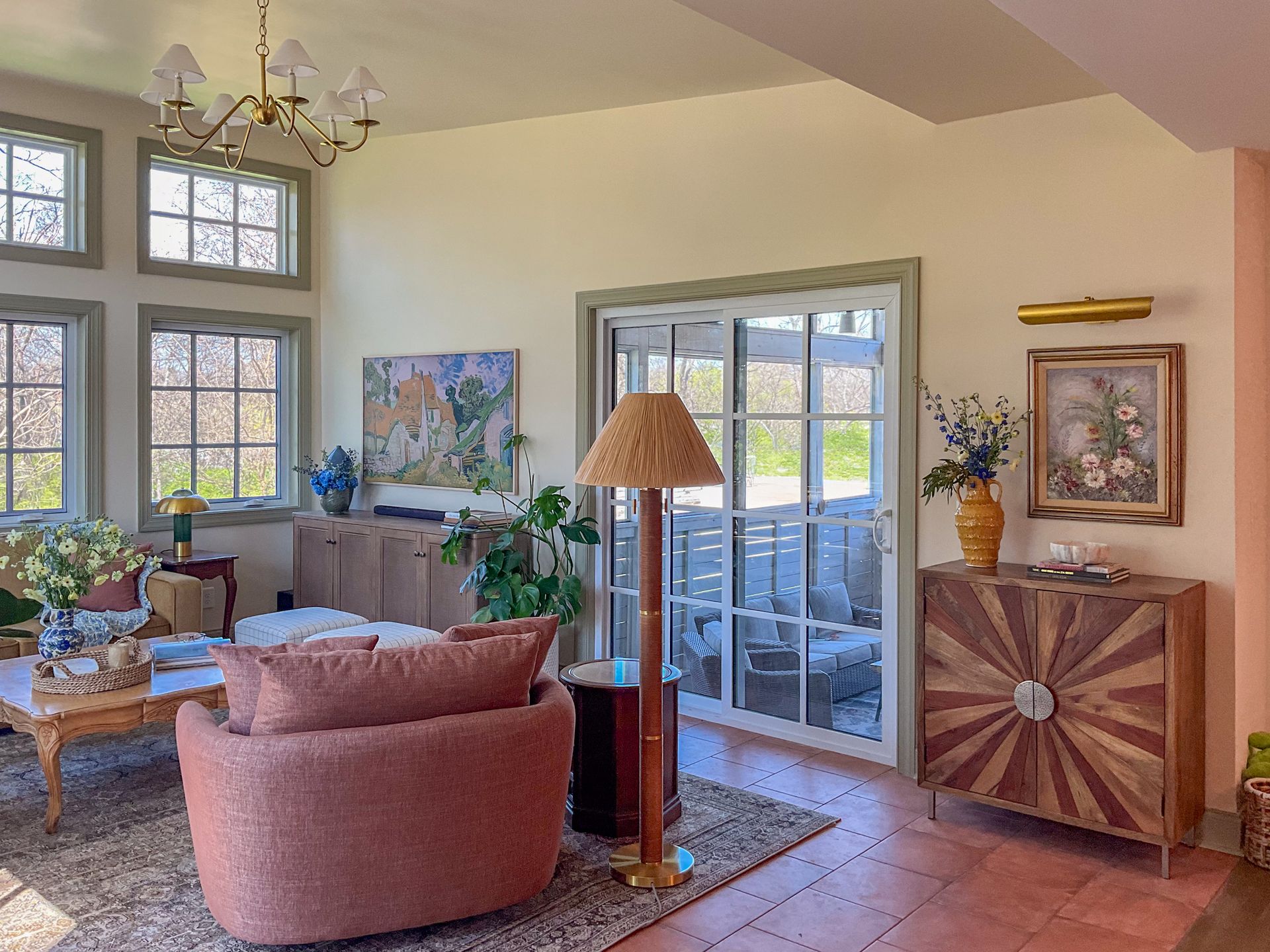 Living room with large windows, peach walls, and wood furniture; cozy seating area with a patterned rug.