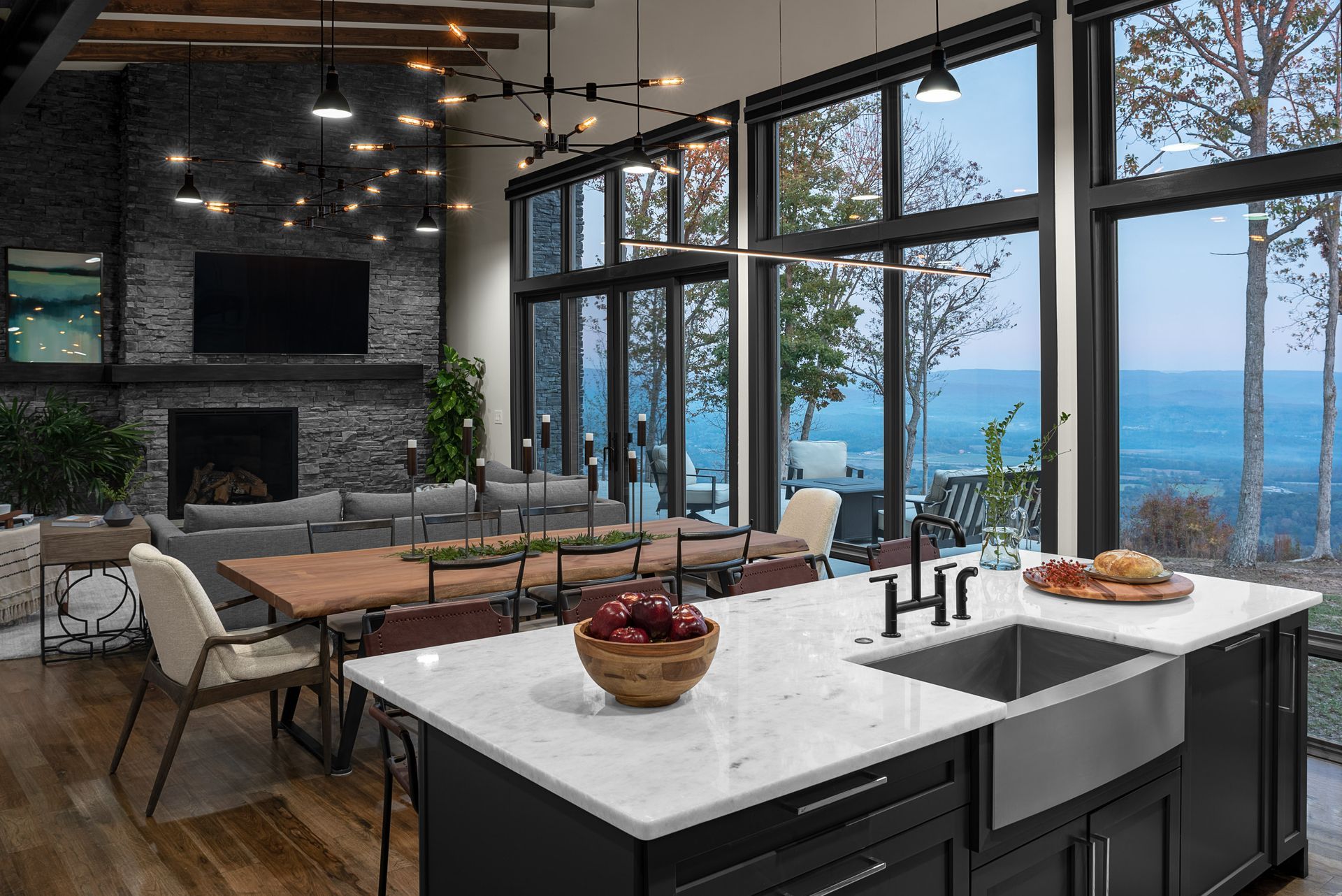 A kitchen with a sink , table , chairs and a view of the ocean.