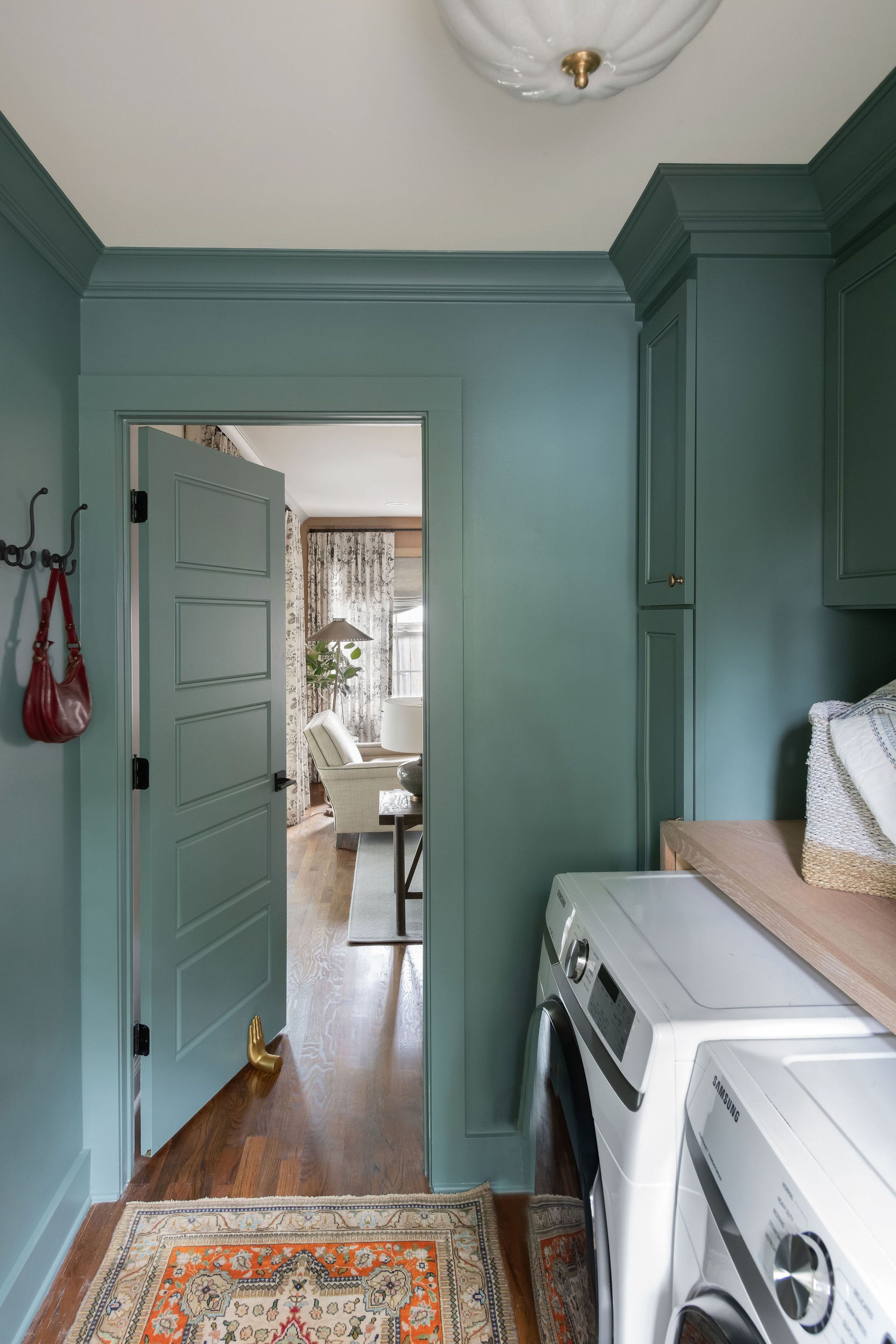Laundry room with teal walls, a door to a living room, and a washer and dryer.