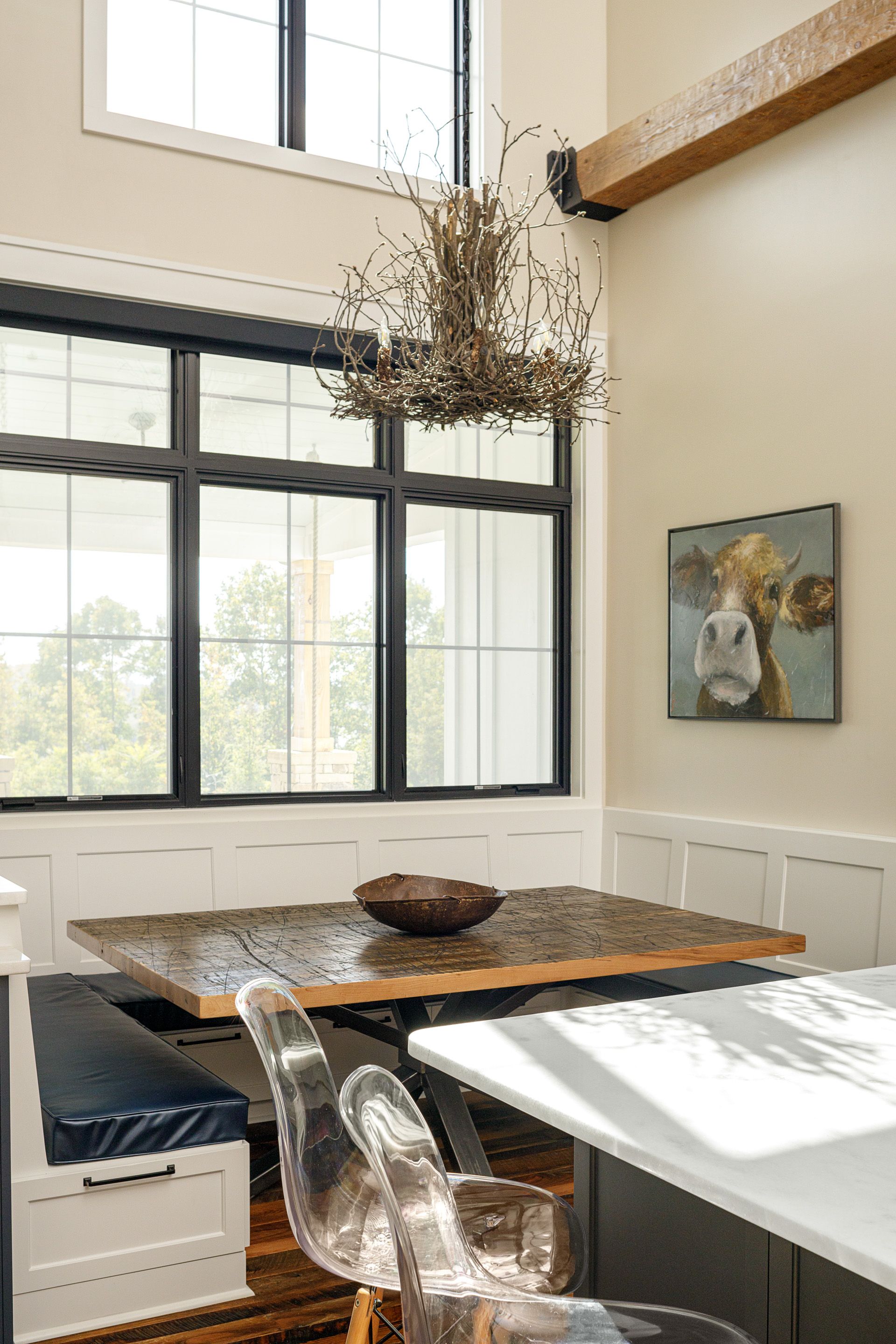 A kitchen with a table and chairs and a painting of a cow on the wall.