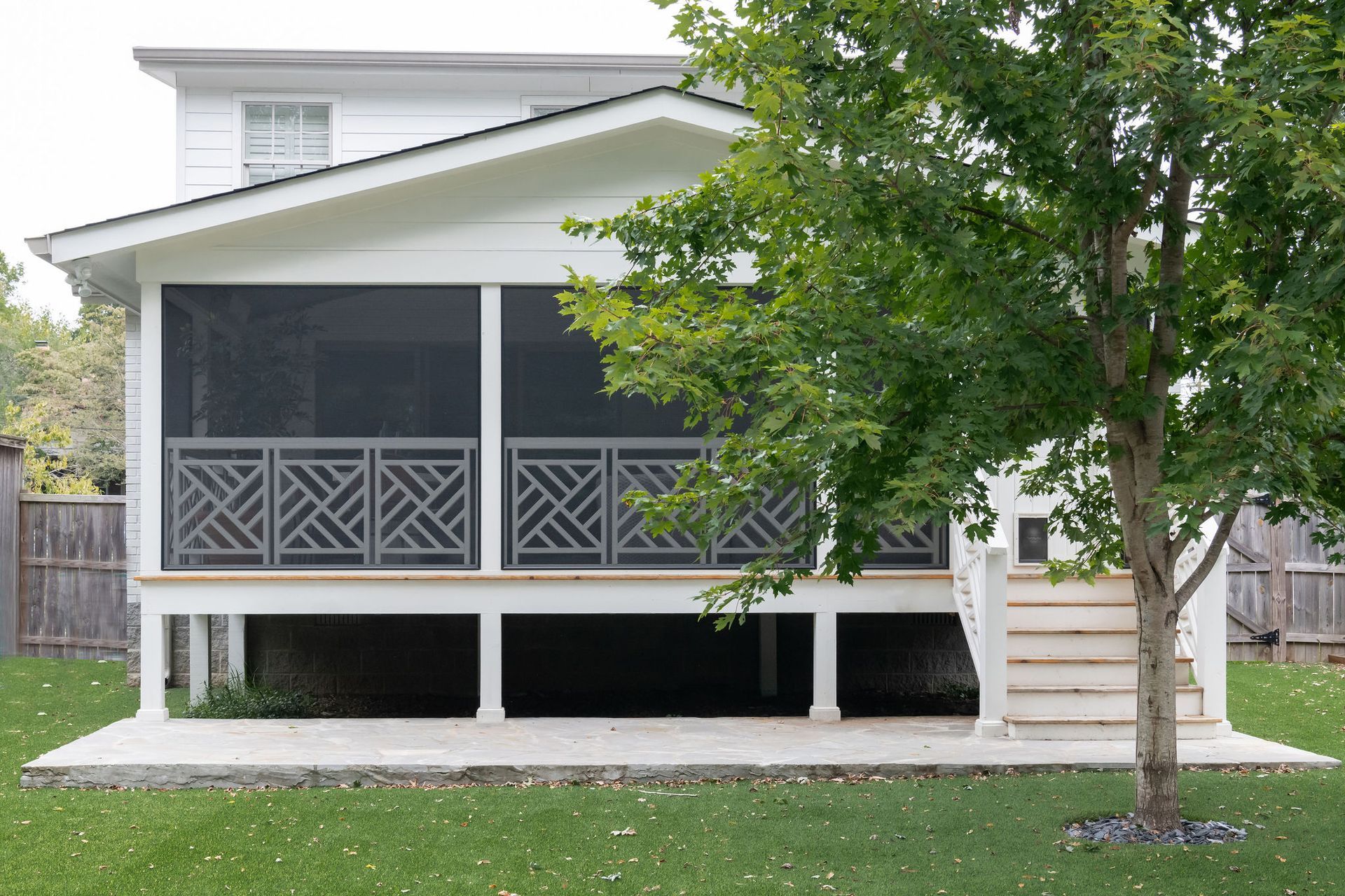 A white house with a screened in porch and stairs.