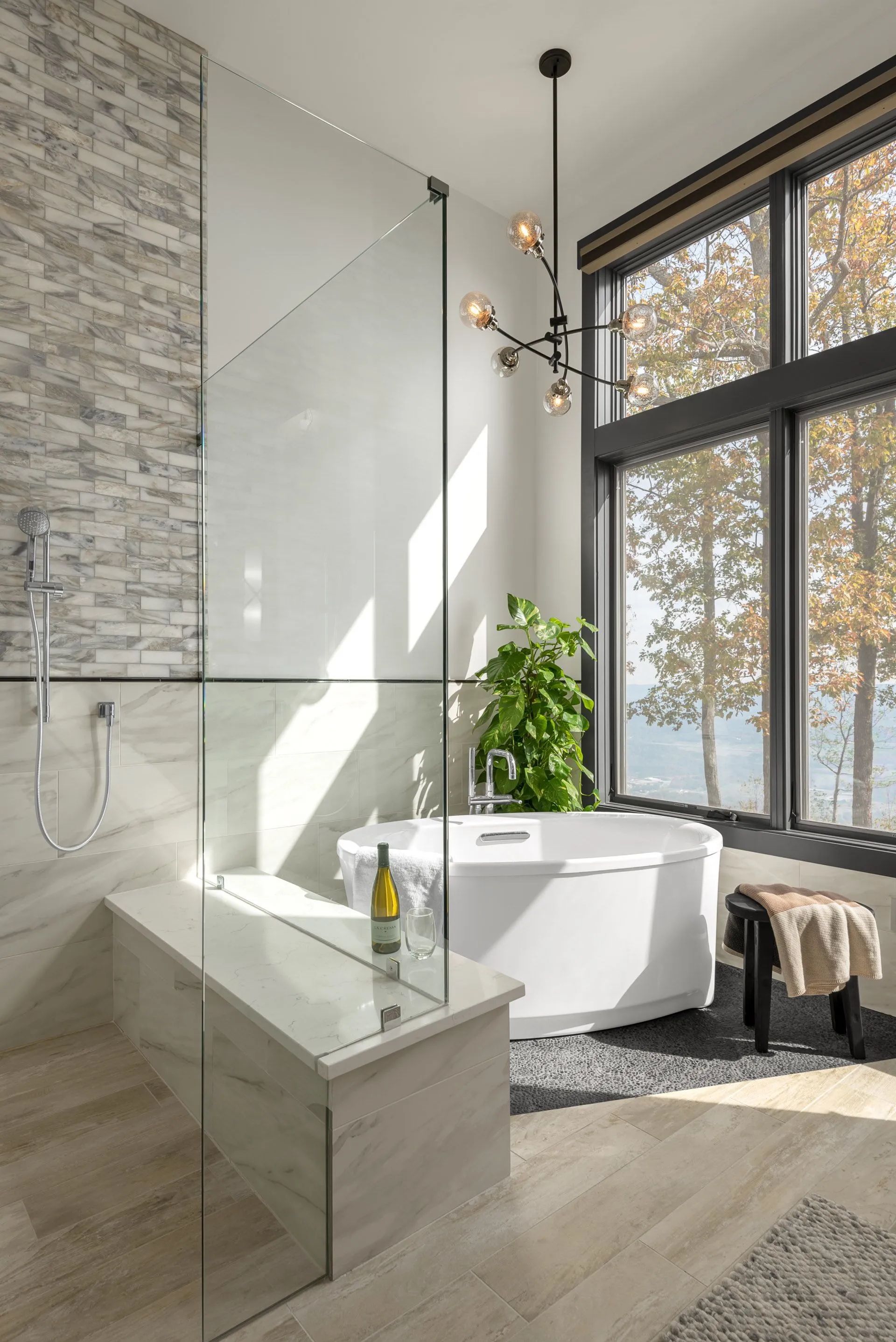 A bathroom with a tub , shower , and large windows.