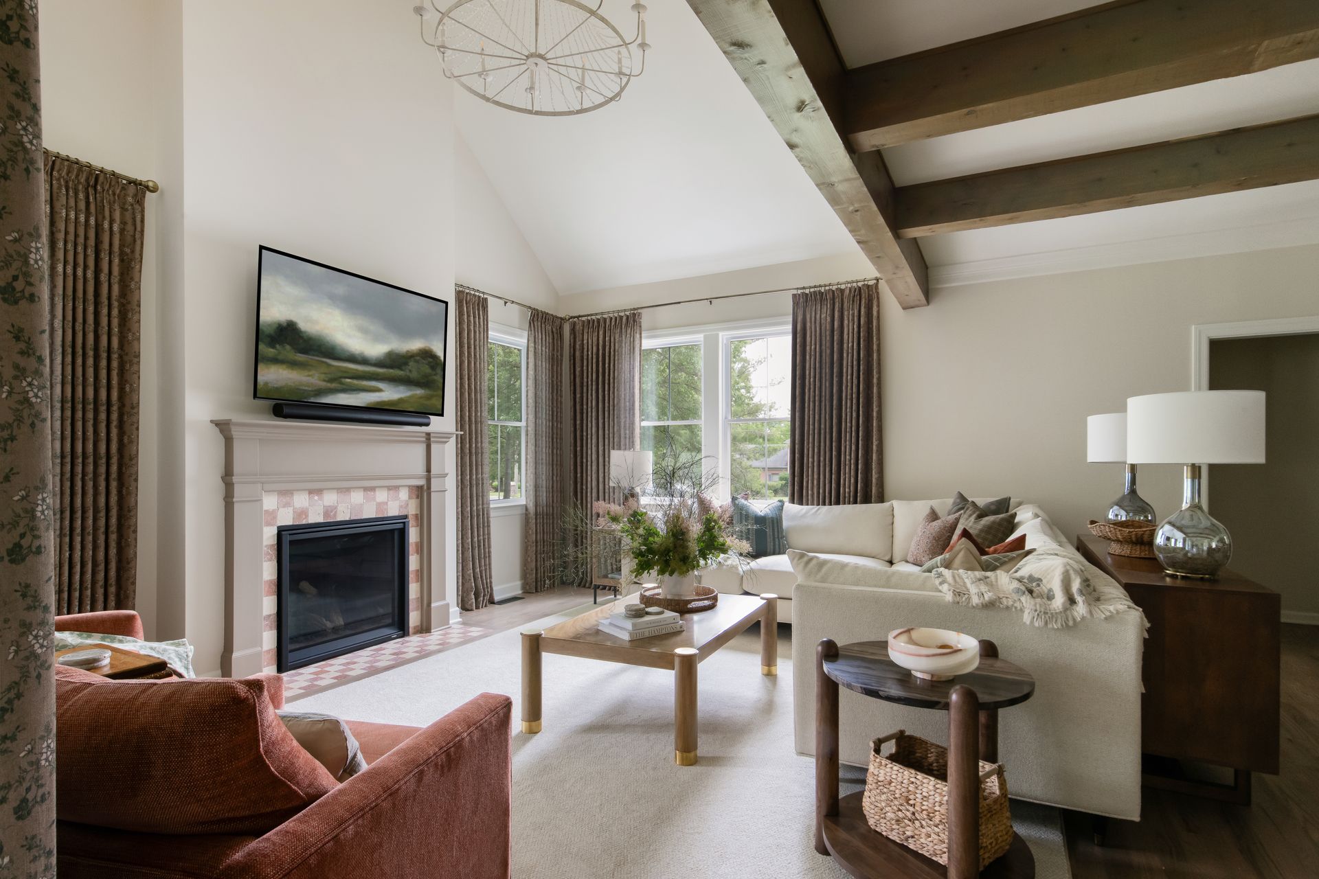 Cozy living room with fireplace, cream sofa, and window seat; neutral tones with wooden beams and accents.
