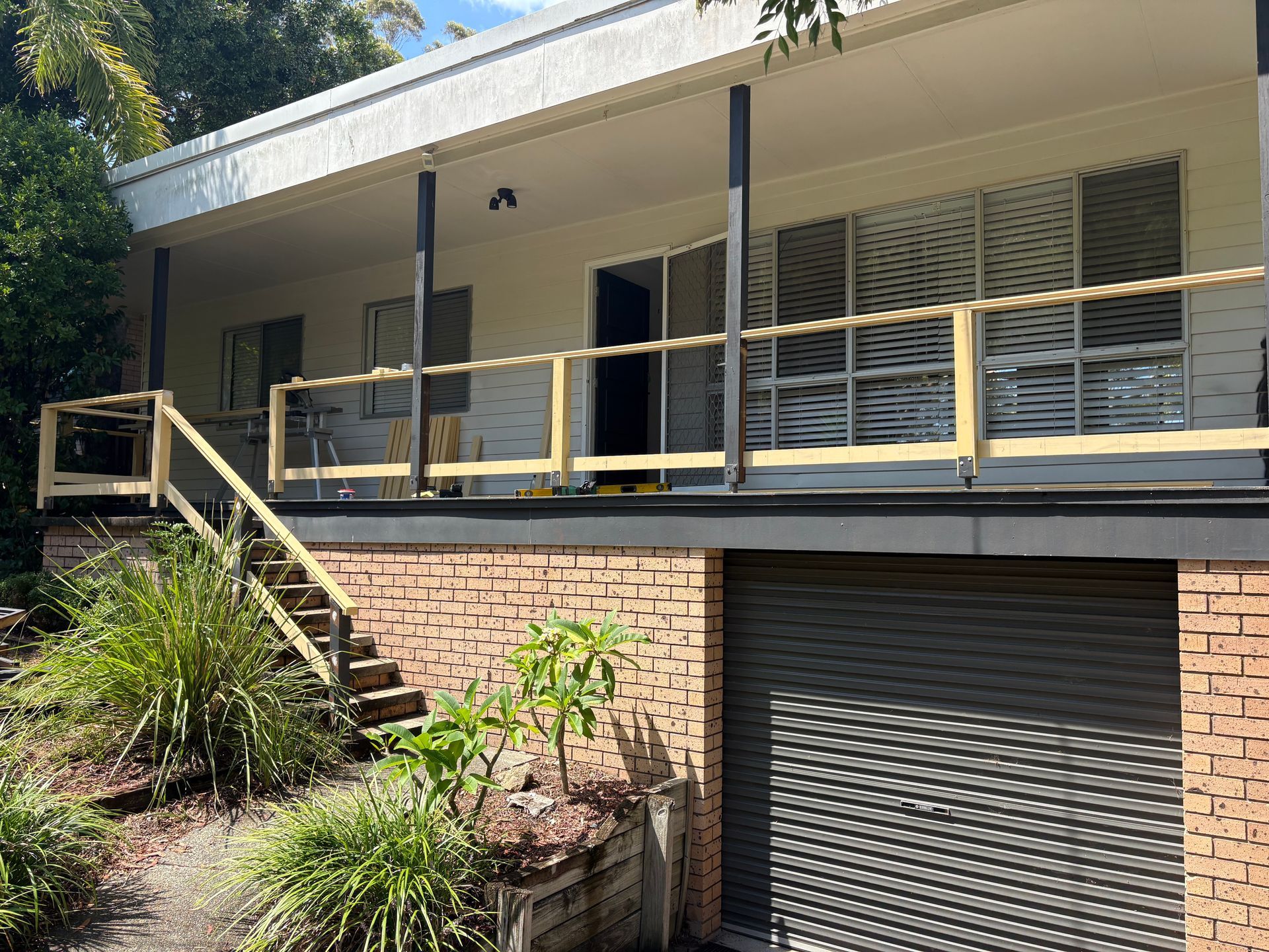 House with brick facade, elevated deck, stairs leading up, garage door — Keystone Property Solutions In Waratah, NSW
