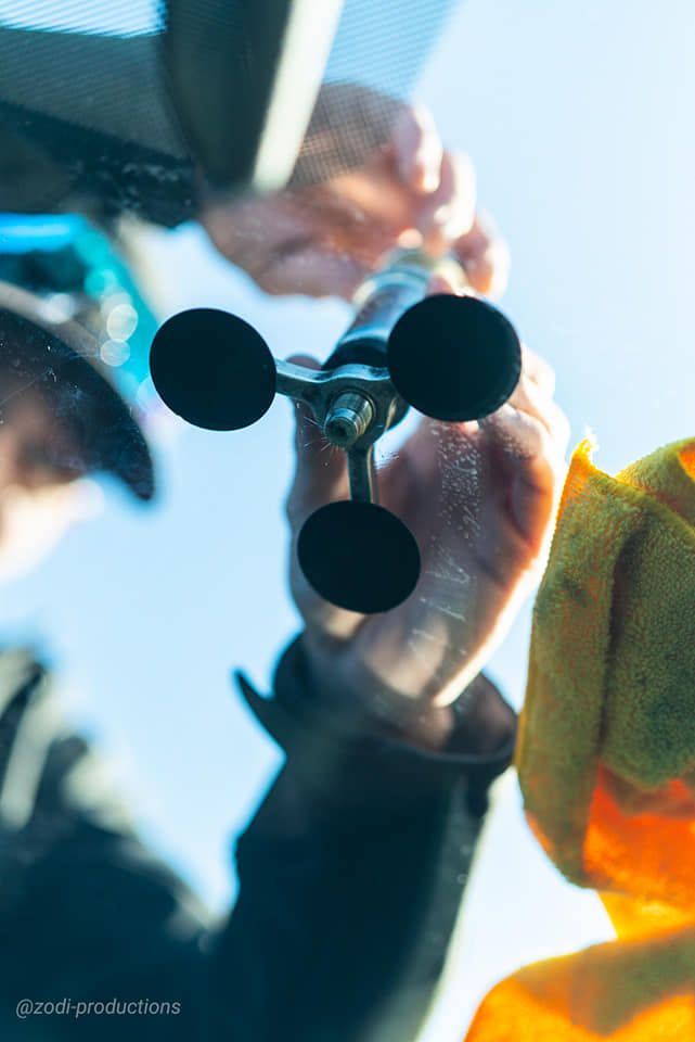 Close-up of hands holding a small black molecular model with colored glassware in the background