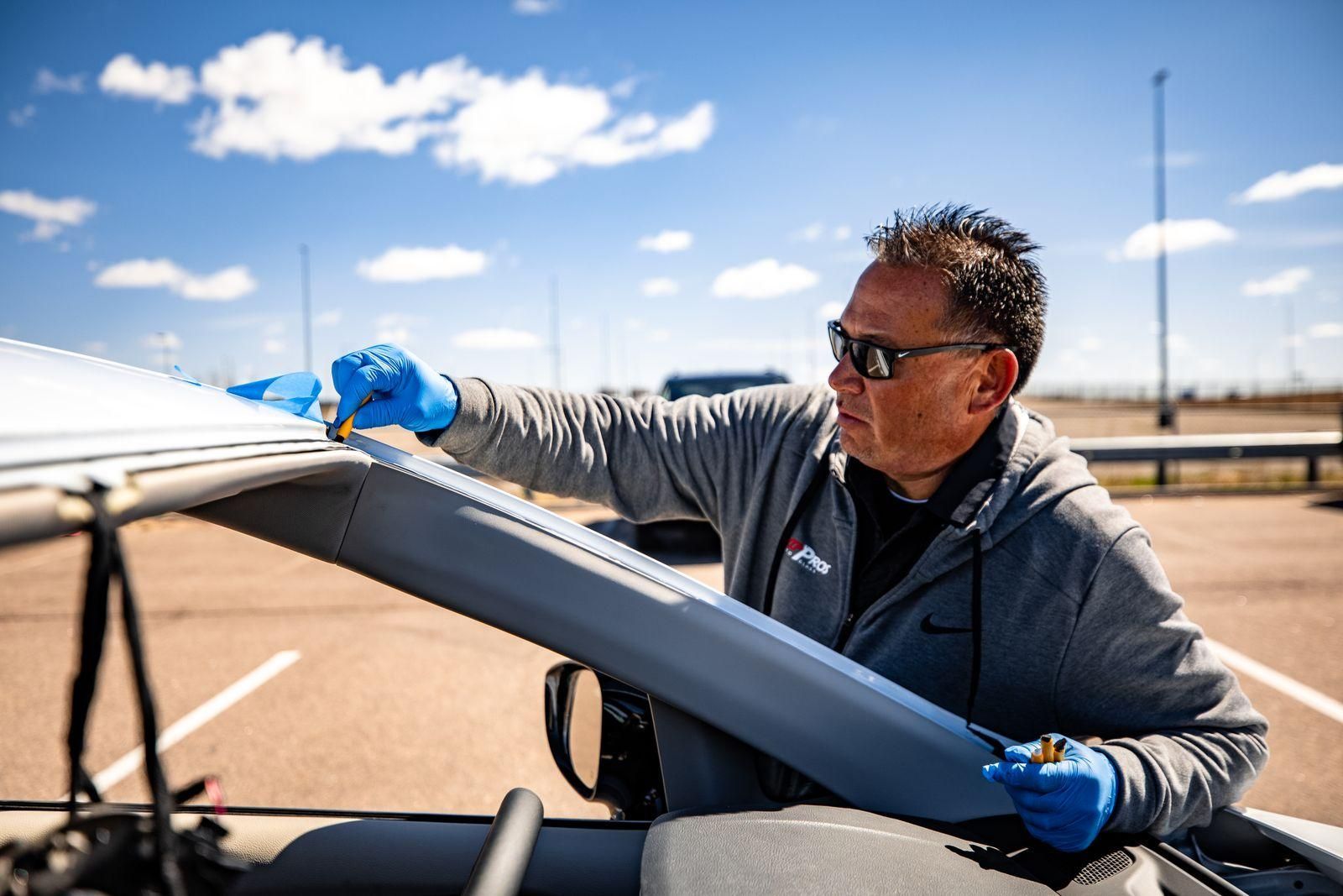 Person in blue gloves inspects a small aircraft wing on a sunny tarmac