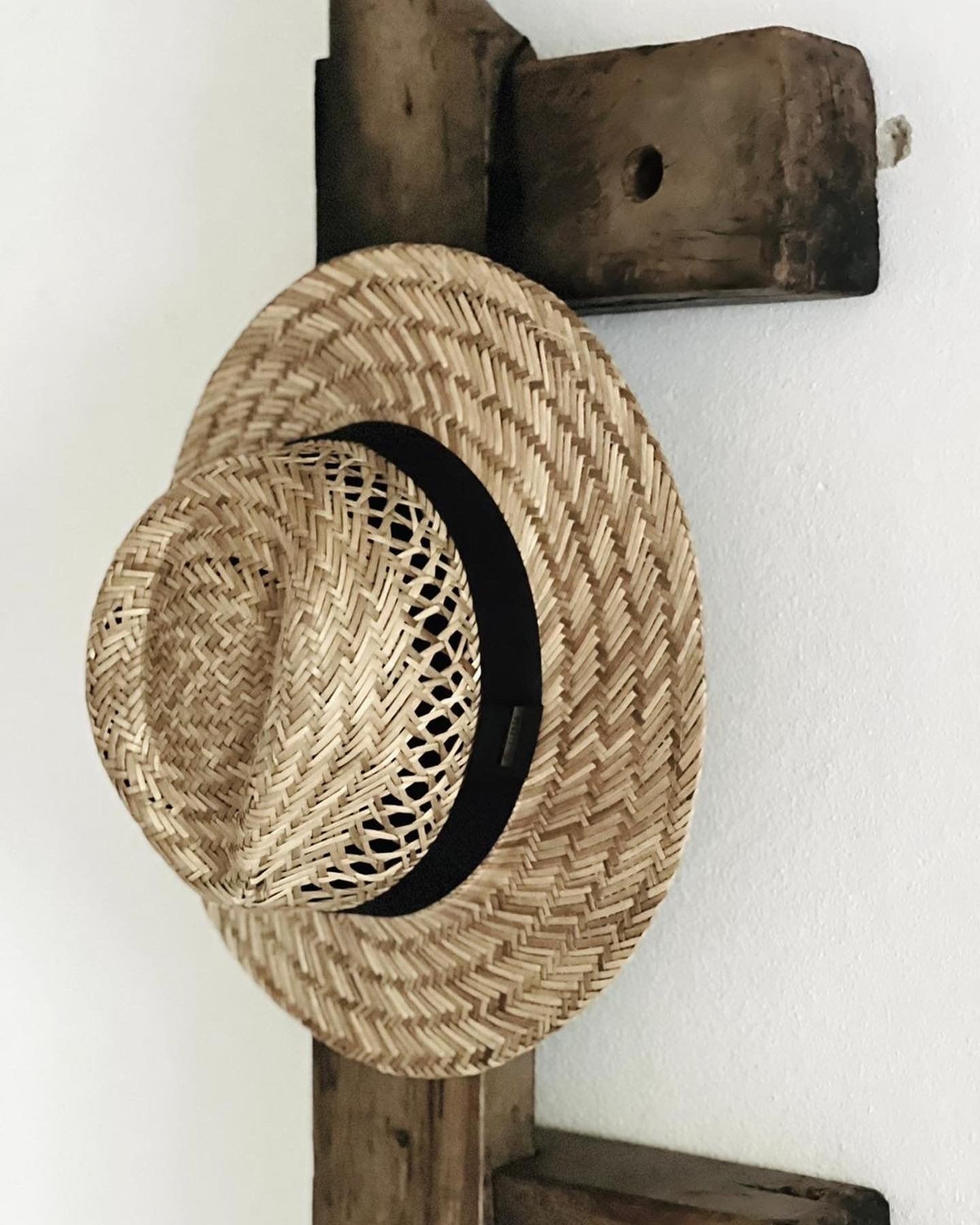Een strohoed hangt aan een houten rek