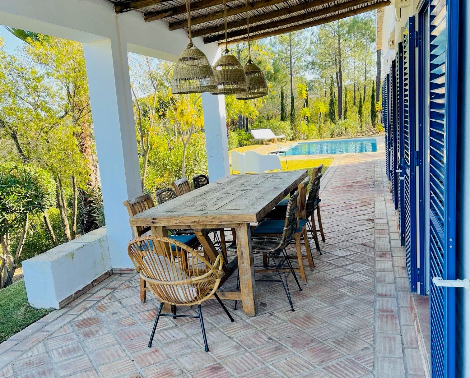 Eine Terrasse mit Tisch und Stühlen und einem Pool im Hintergrund.