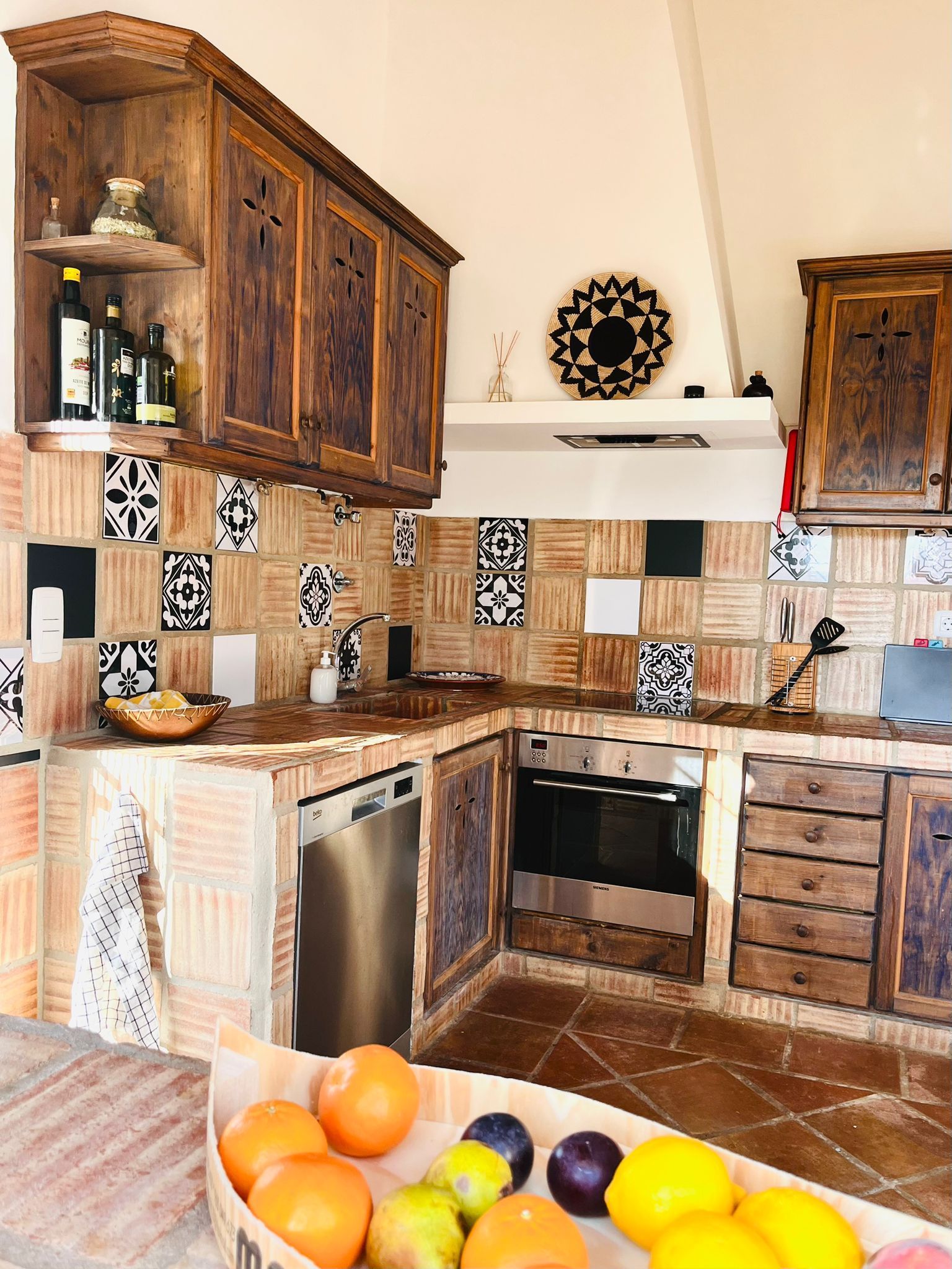 Een keuken met houten kasten en een schaal met fruit op het aanrecht