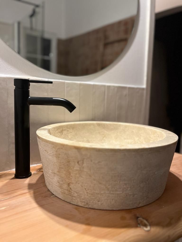 Ein Waschbecken mit schwarzem Wasserhahn und Spiegel.