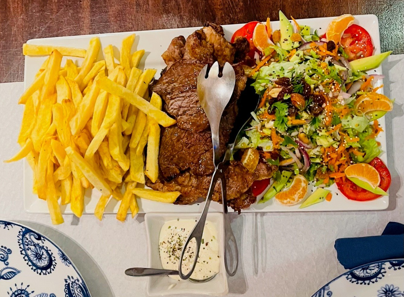 Um prato de comida com batatas fritas e uma salada em uma mesa
