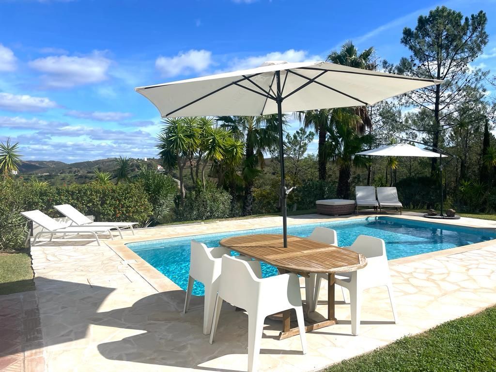 Ein Swimmingpool mit Tisch und Stühlen unter einem Sonnenschirm.