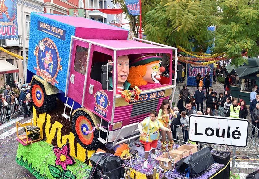 Een clown zit achter op een vrachtwagen tijdens een parade.