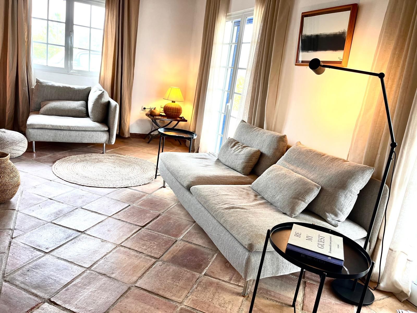 Een woonkamer met een bank, stoel, tafel en lamp.
