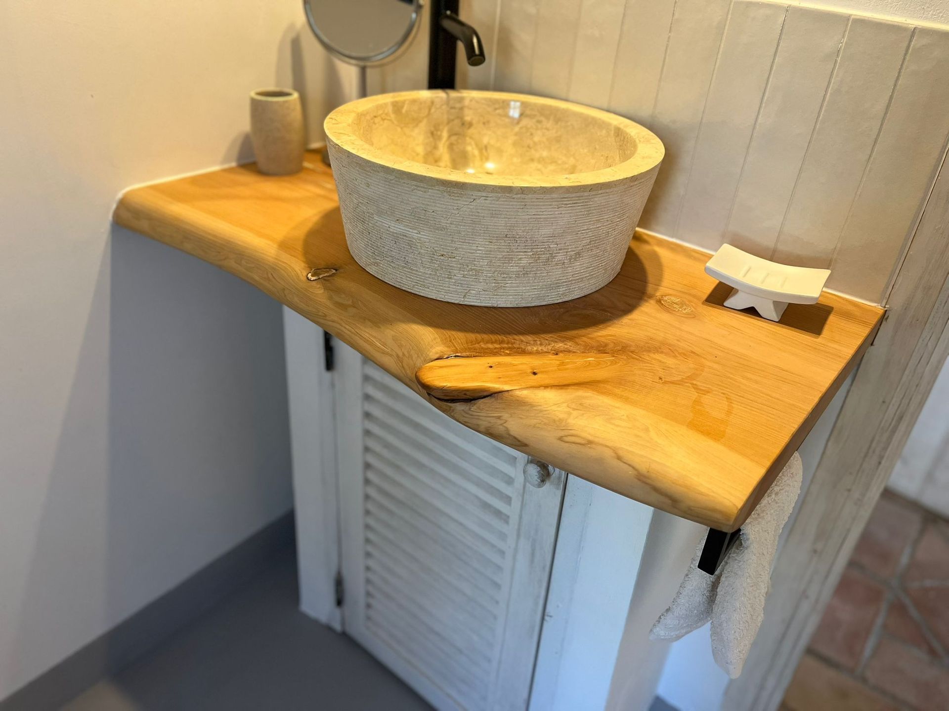 Ein Badezimmer mit einem Waschbecken und einem Spiegel auf einer Holzablage.