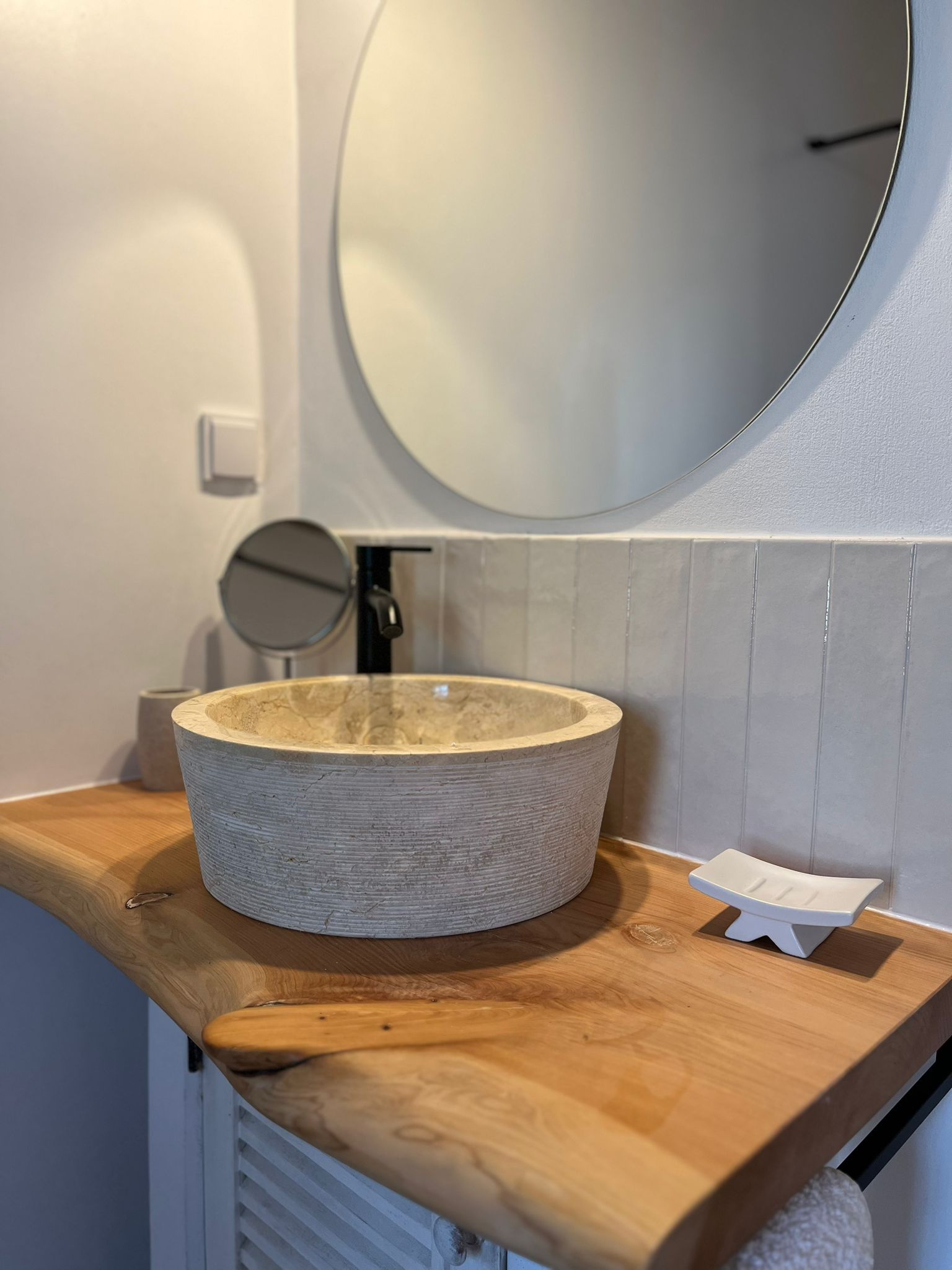 Ein Badezimmer mit einem Waschbecken und einem Spiegel auf einer Holzablage.