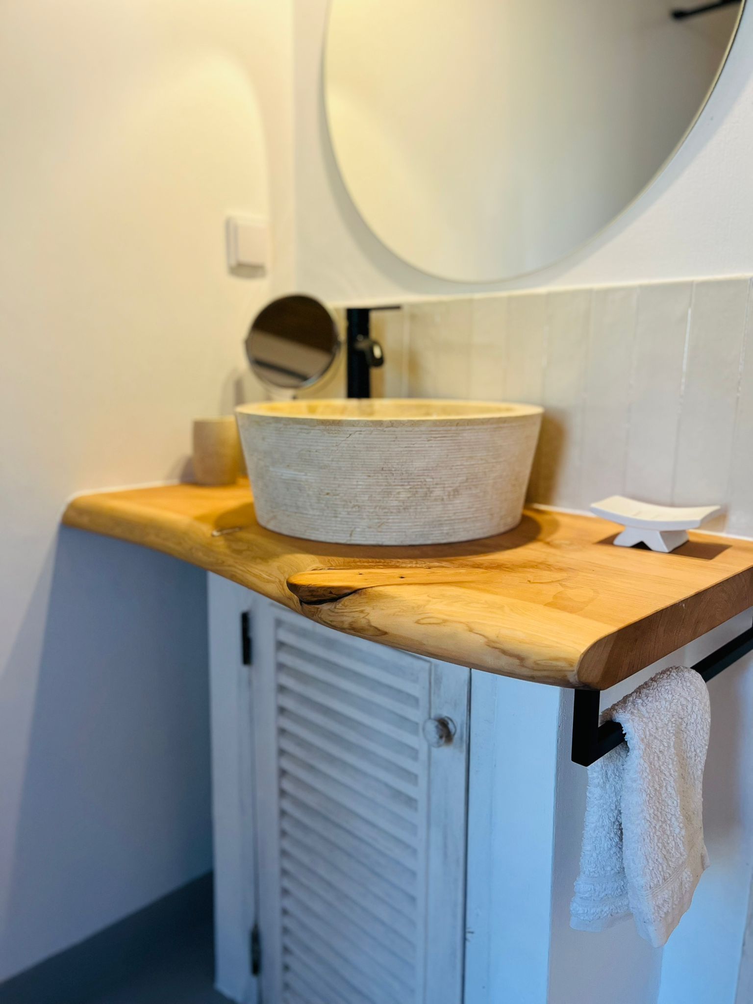 Een badkamer met een wastafel, spiegel en handdoekenrek