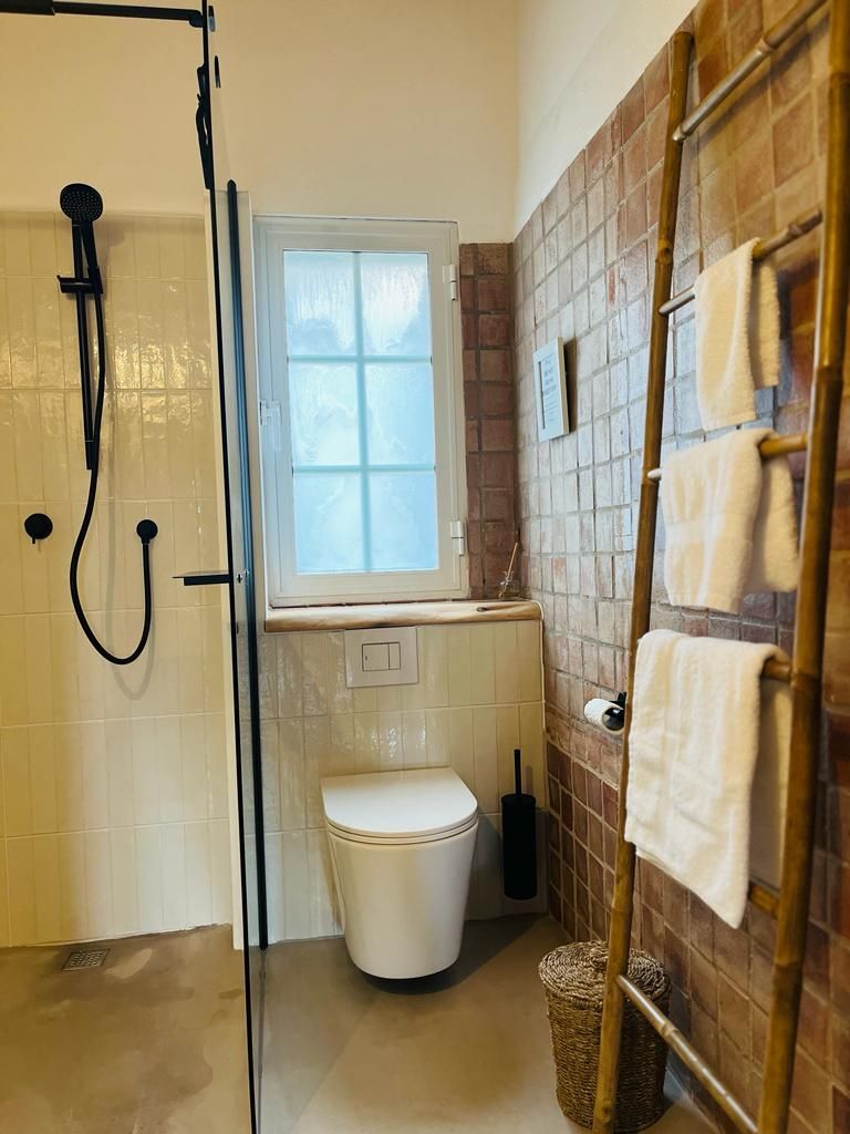 Ein Badezimmer mit Toilette, Dusche und Leiter.