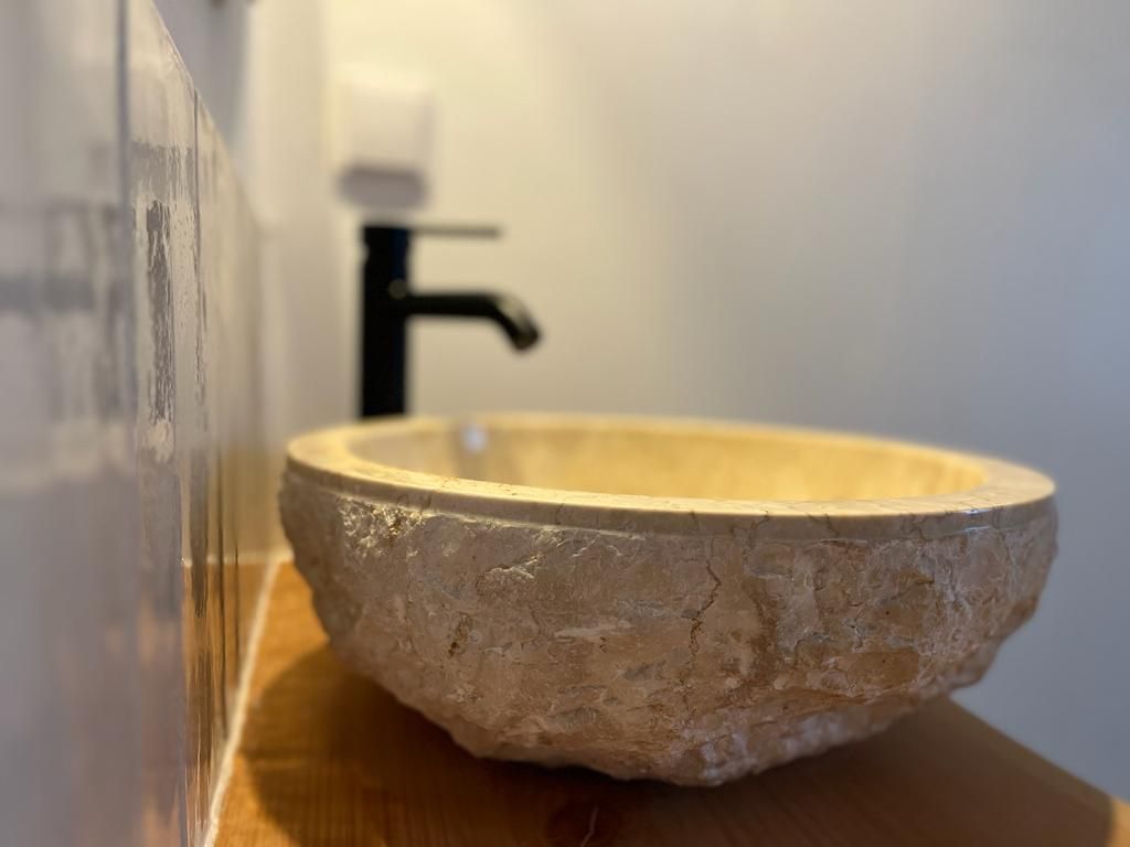 Ein Badezimmer mit einem Steinwaschbecken und einem schwarzen Wasserhahn.