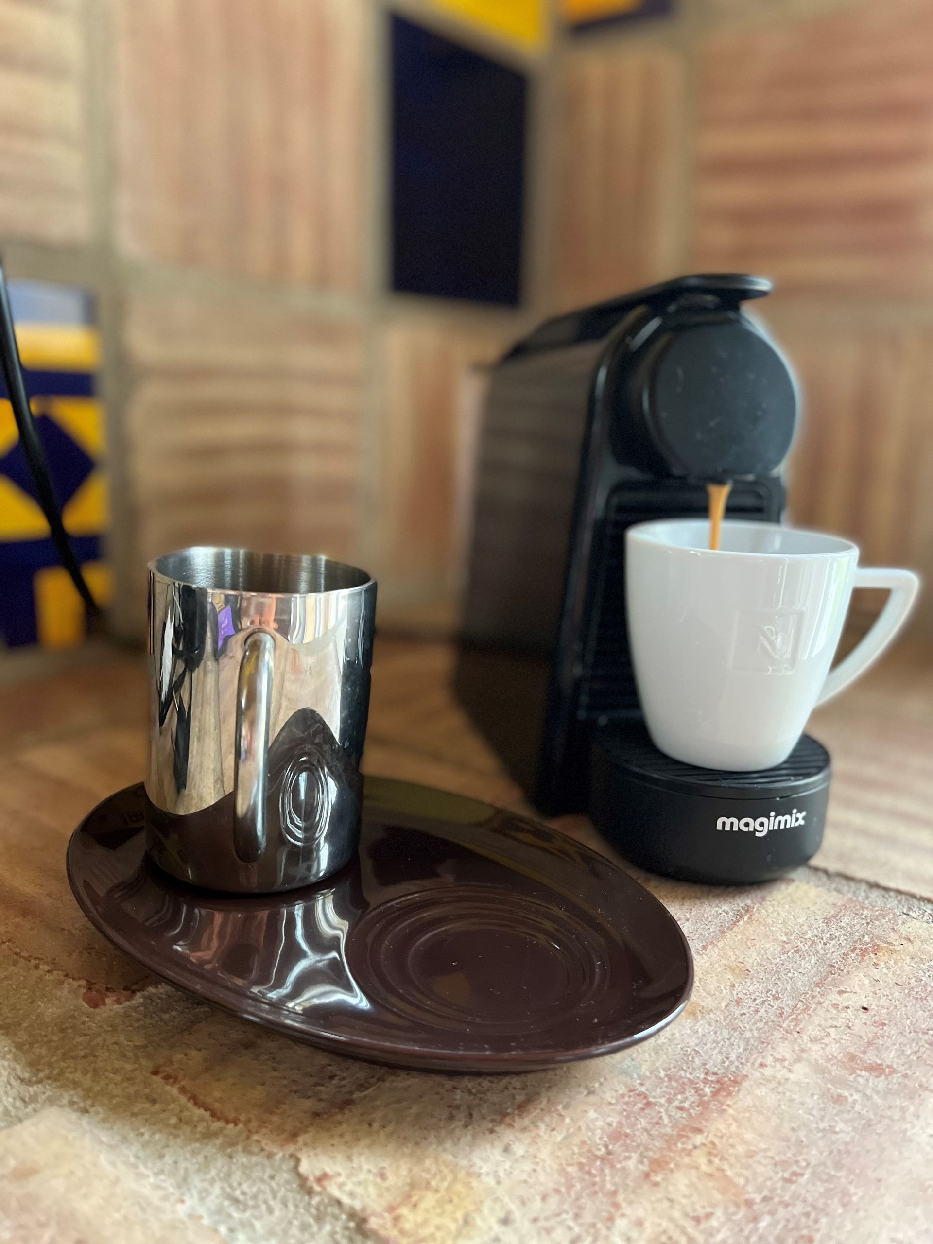 Eine Tasse Kaffee steht auf einer Untertasse neben einer Kaffeemaschine.