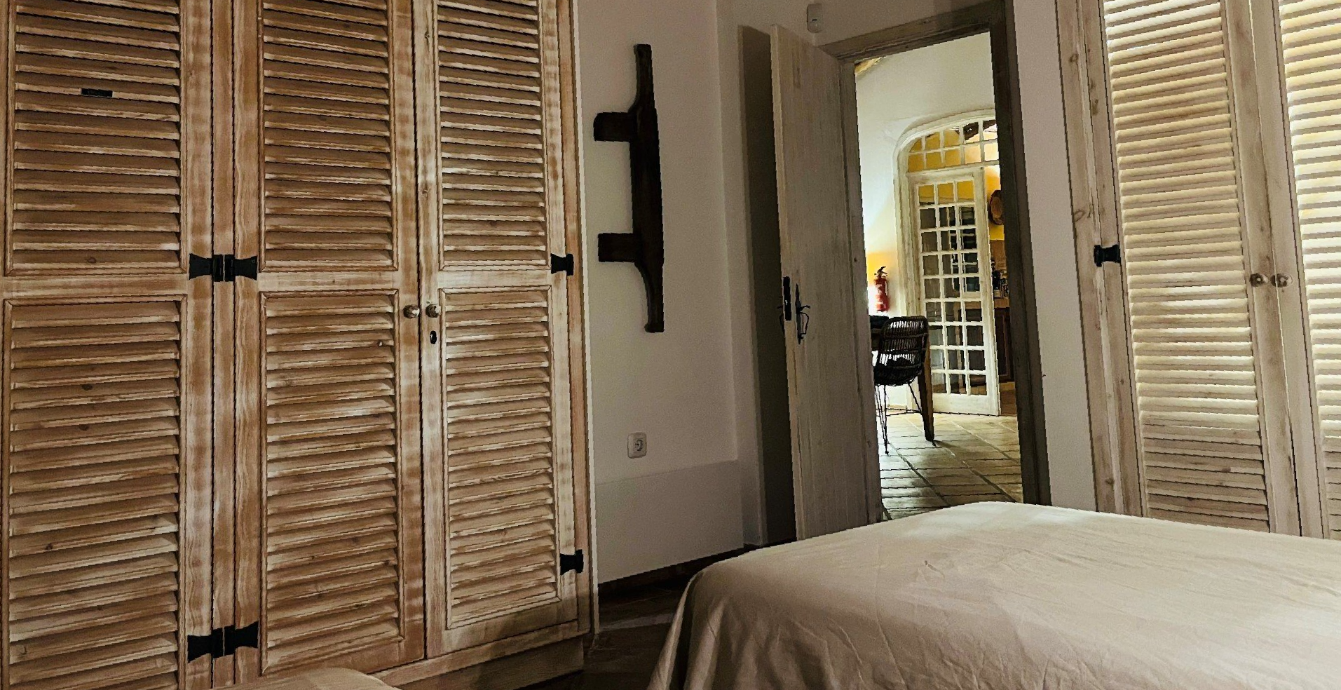 Een slaapkamer met een bed, kasten en luiken.