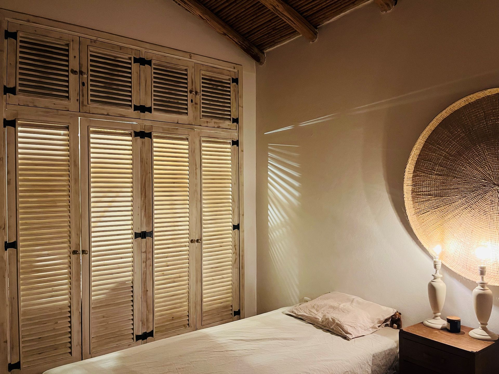 Ein Schlafzimmer mit Bett, Nachttisch, Lampe und Kleiderschrank.