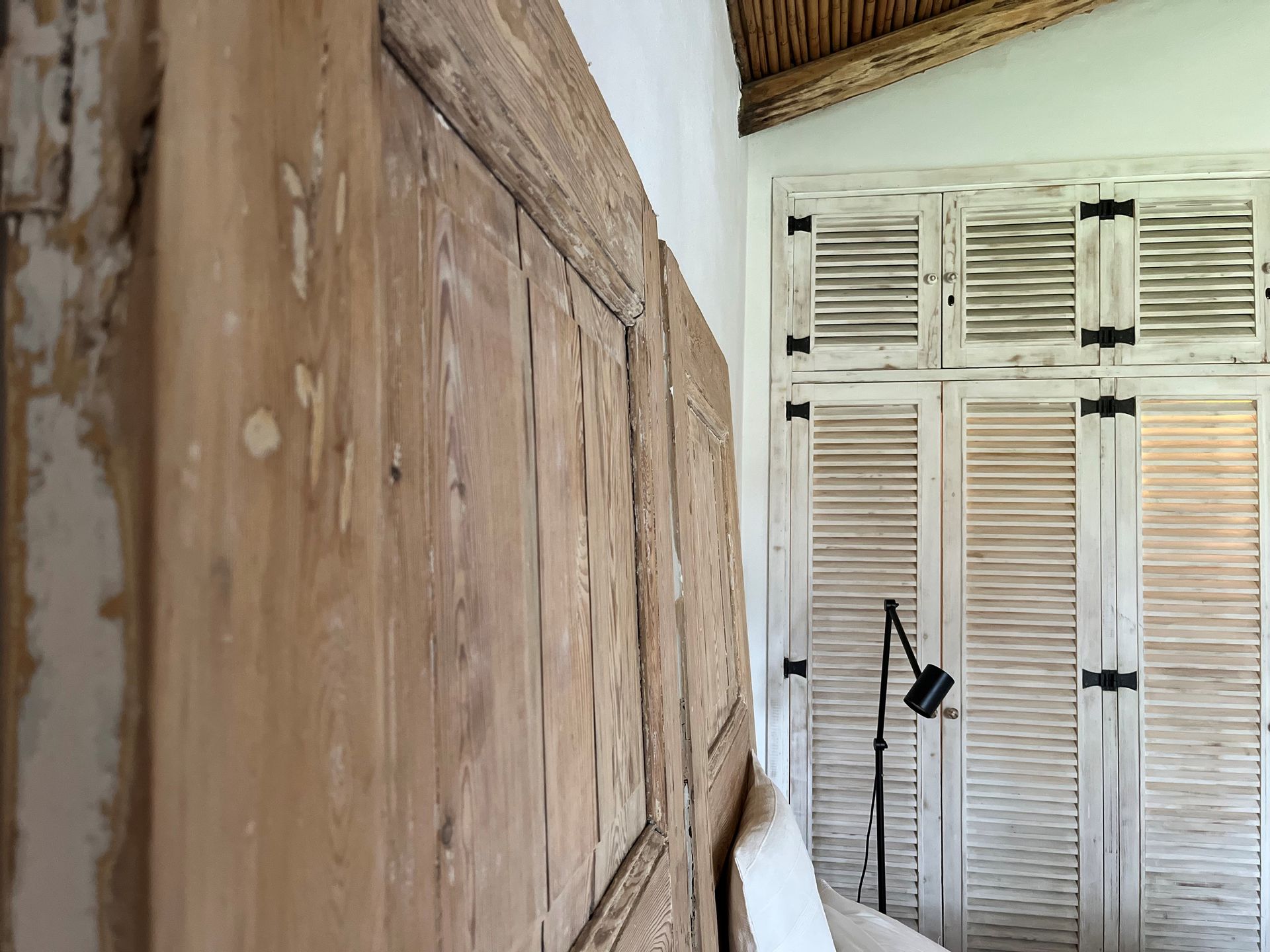 Ein Schlafzimmer mit Holzkopfteil und Fensterläden an den Wänden.