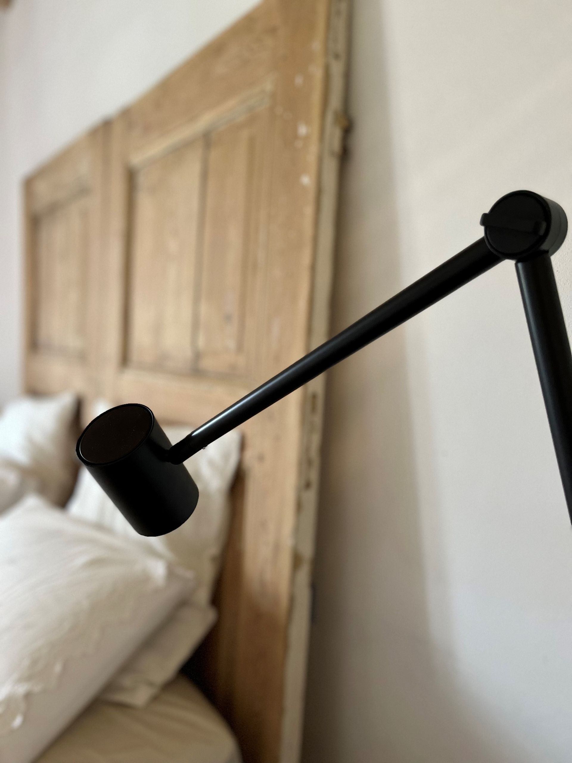 Eine schwarze Lampe sitzt vor einem hölzernen Kopfteil
