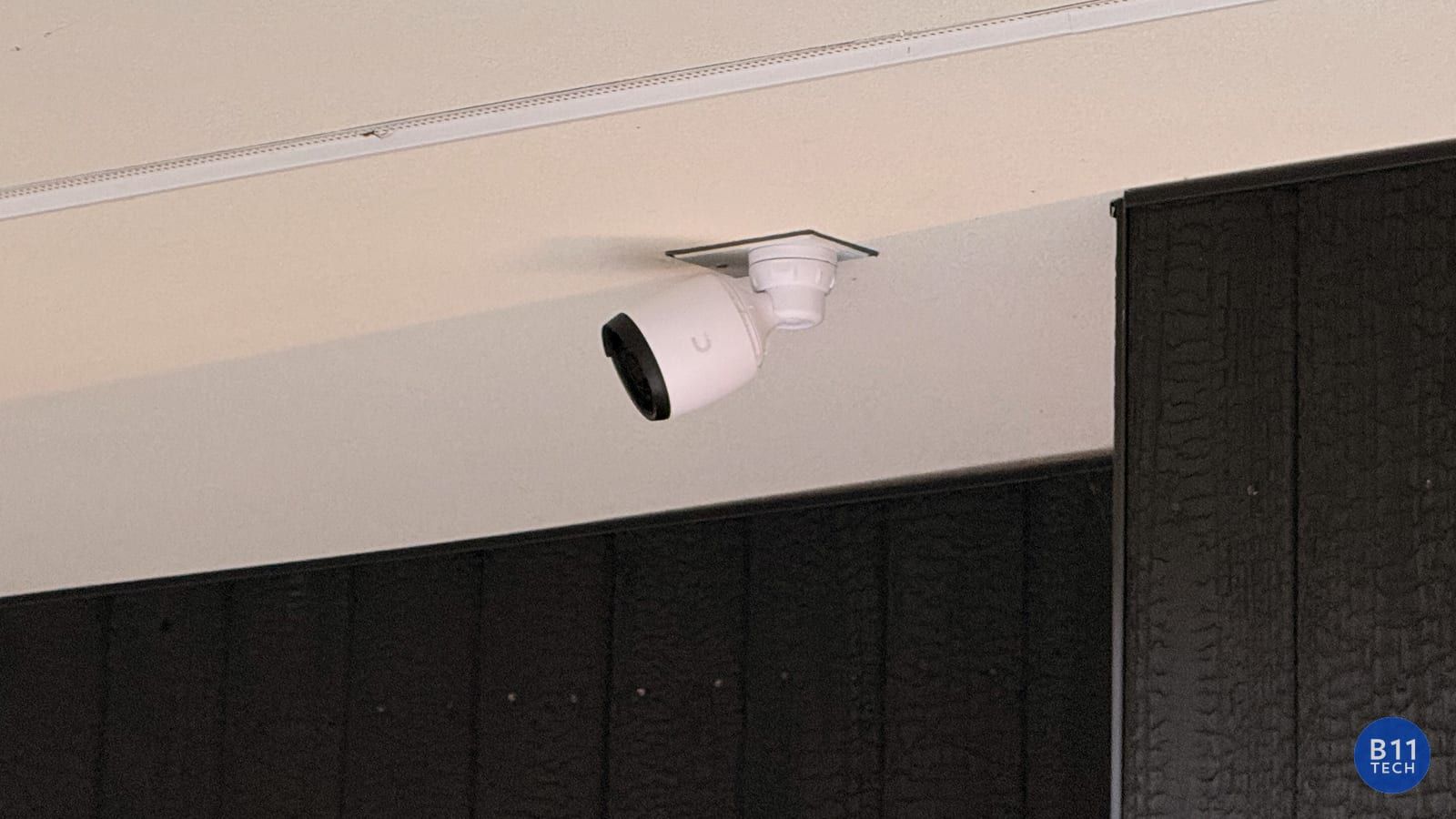 Real B11 Tech installation of a white UniFi security camera mounted beneath an exterior overhang