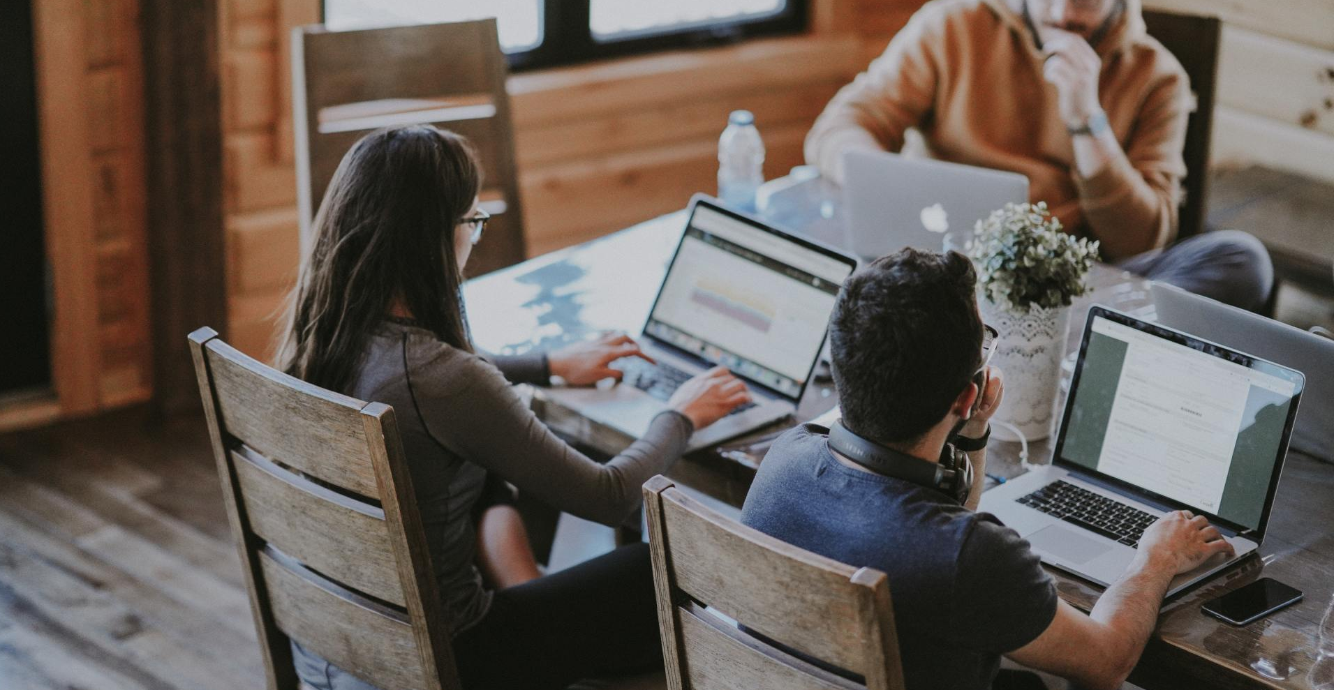 A group of people are sitting at a table with laptops.