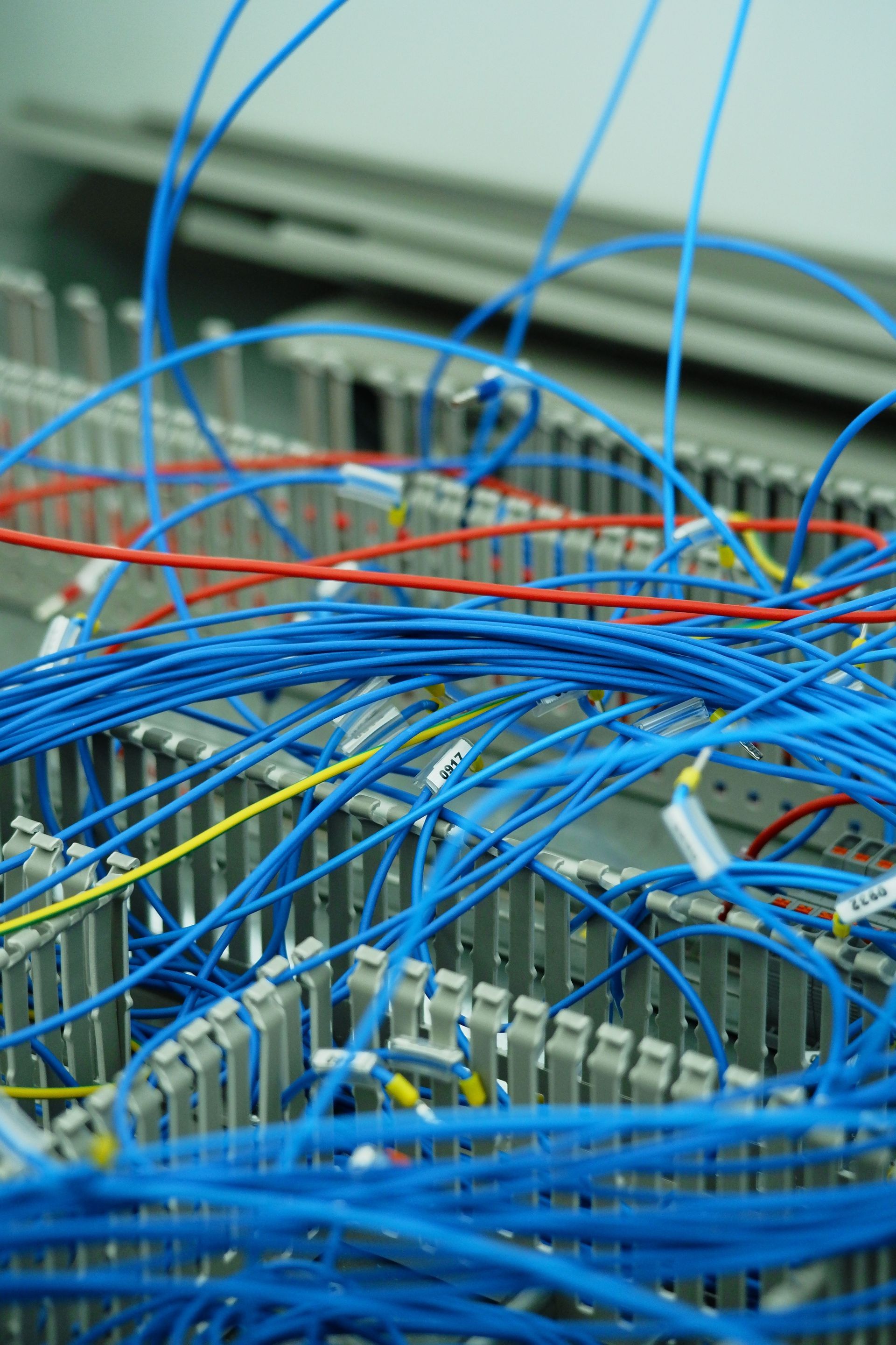 Blue network cables tangled over a server rack with red wires in a data center