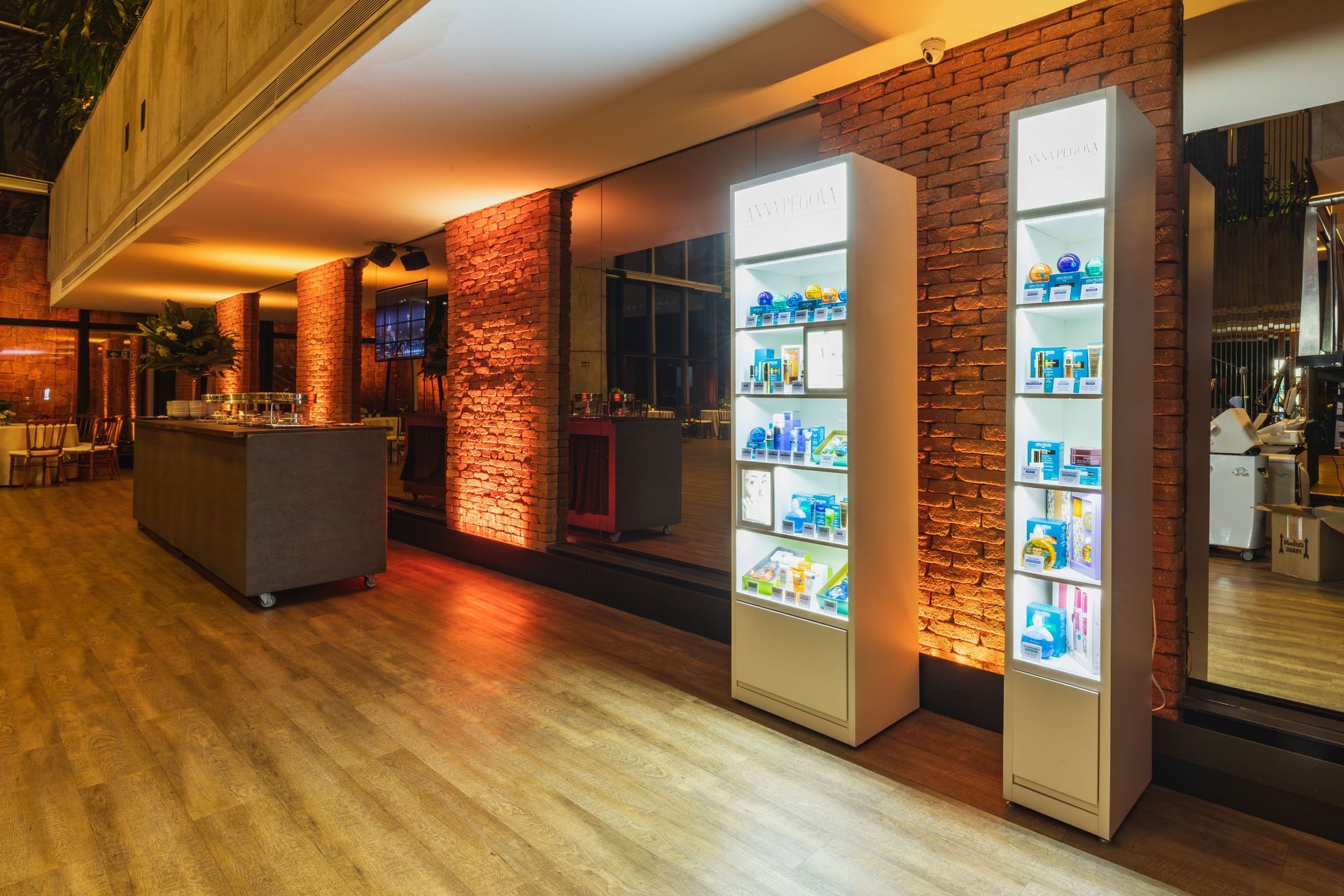 Modern lobby with brick walls, wood floor, and illuminated display cases along the right side.