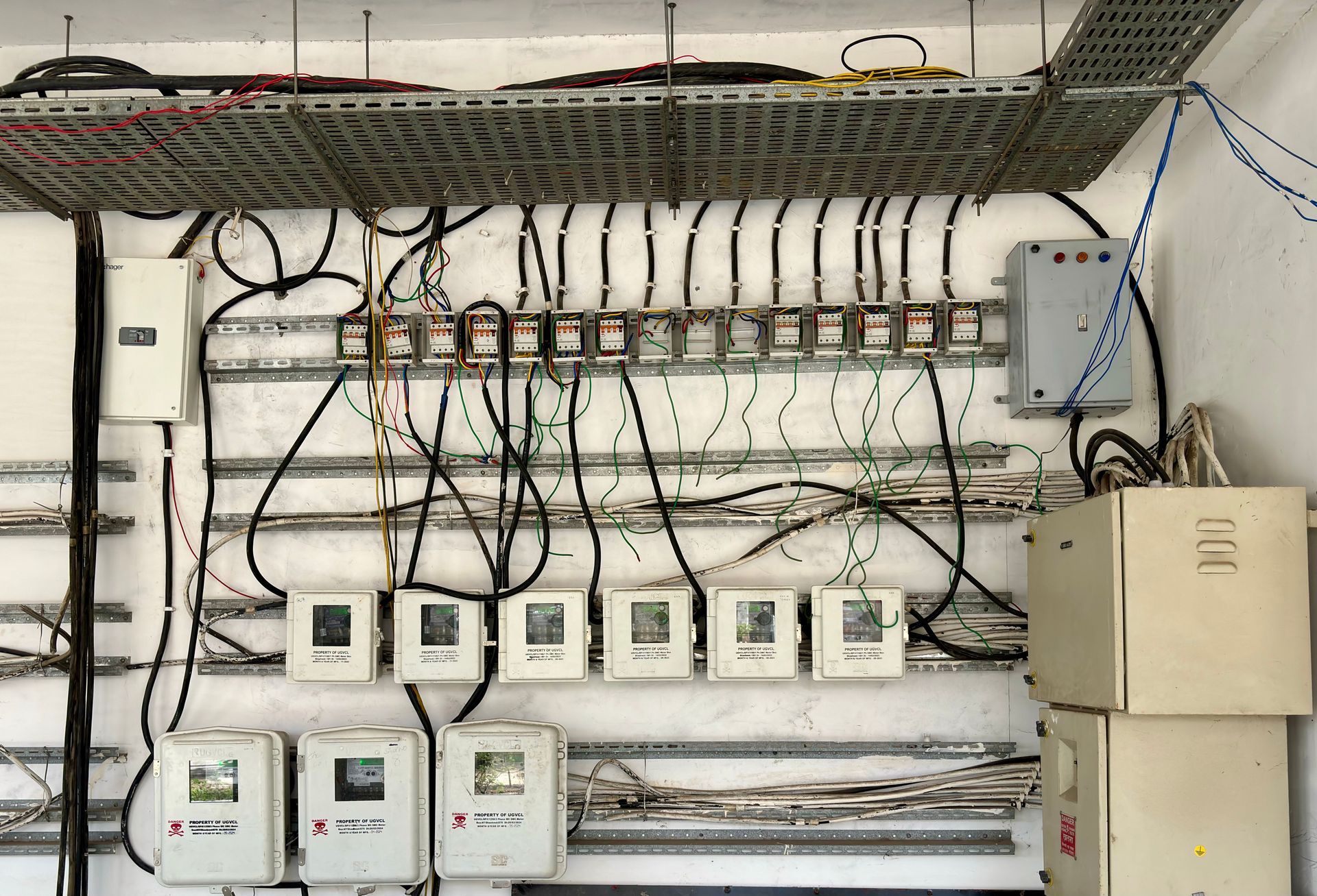 Electrical control panel with rows of wires, meters, and switches mounted on a wall